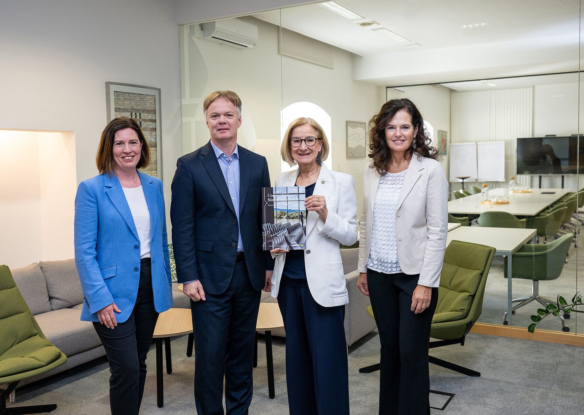 Maria-Luise Fröch, Michael Duscher, Landeshauptfrau Johanna Mikl-Leitner und Edith Mader stehen im Stift Klosterneuburg anlässlich 20 Jahre Convention Bureau Niederösterreich; Mikl-Leitner hält eine Convention-Broschüre in die Kamera.