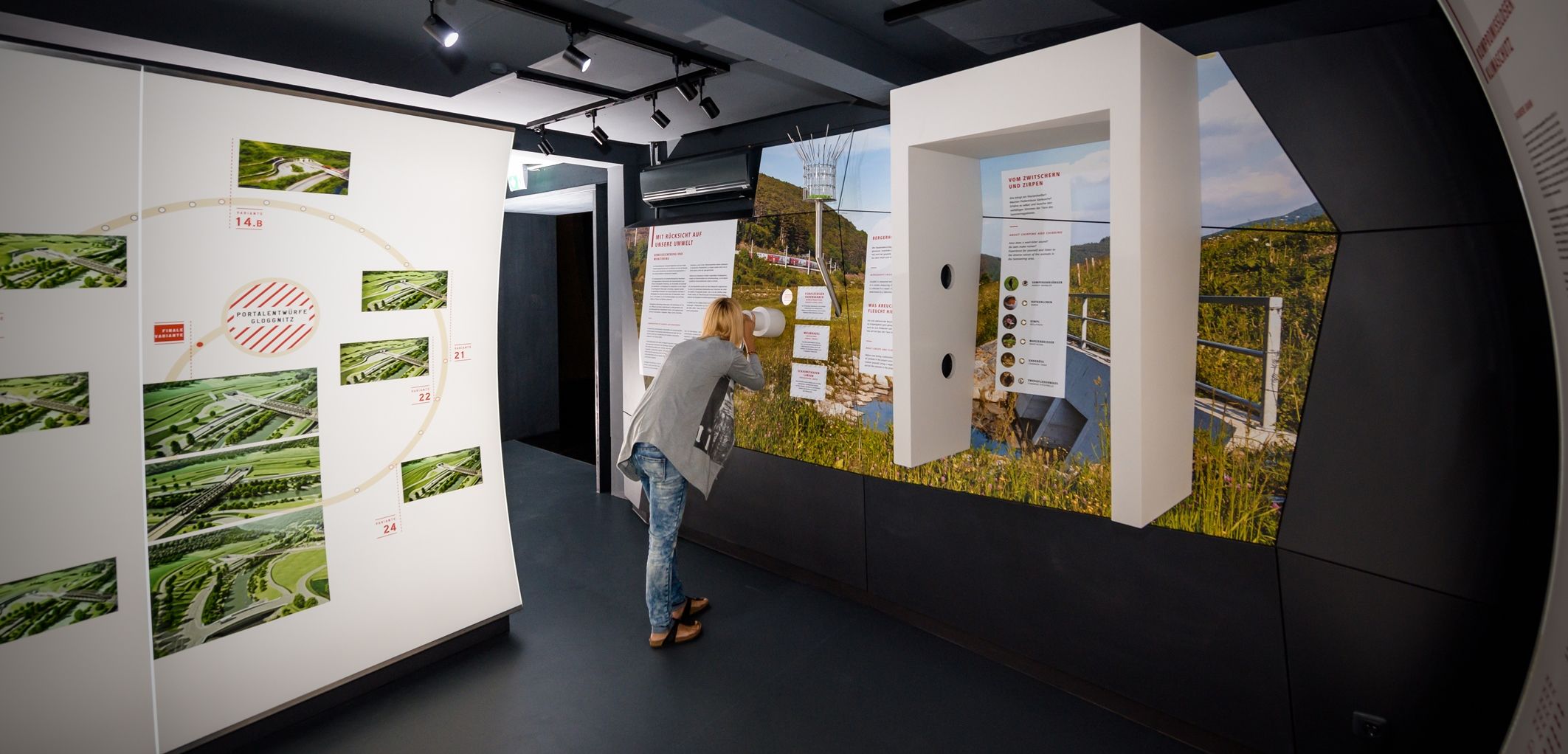 Eine Person betrachtet eine Ausstellung in einem modernen Informationszentrum mit Bildern und Texten an den Wänden.