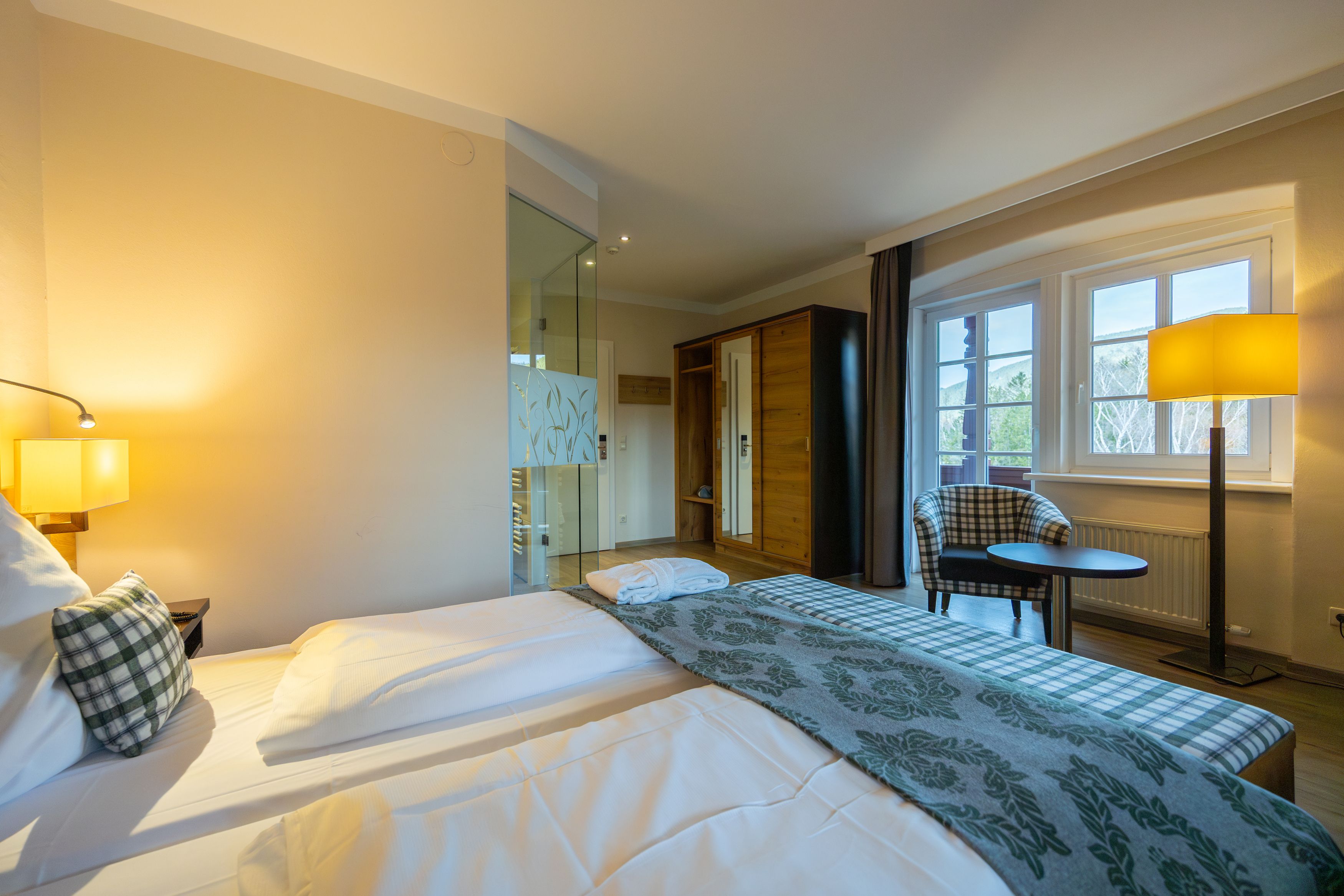 Hotelzimmer mit Doppelbett, Sessel, Tisch und Fenster mit Ausblick.