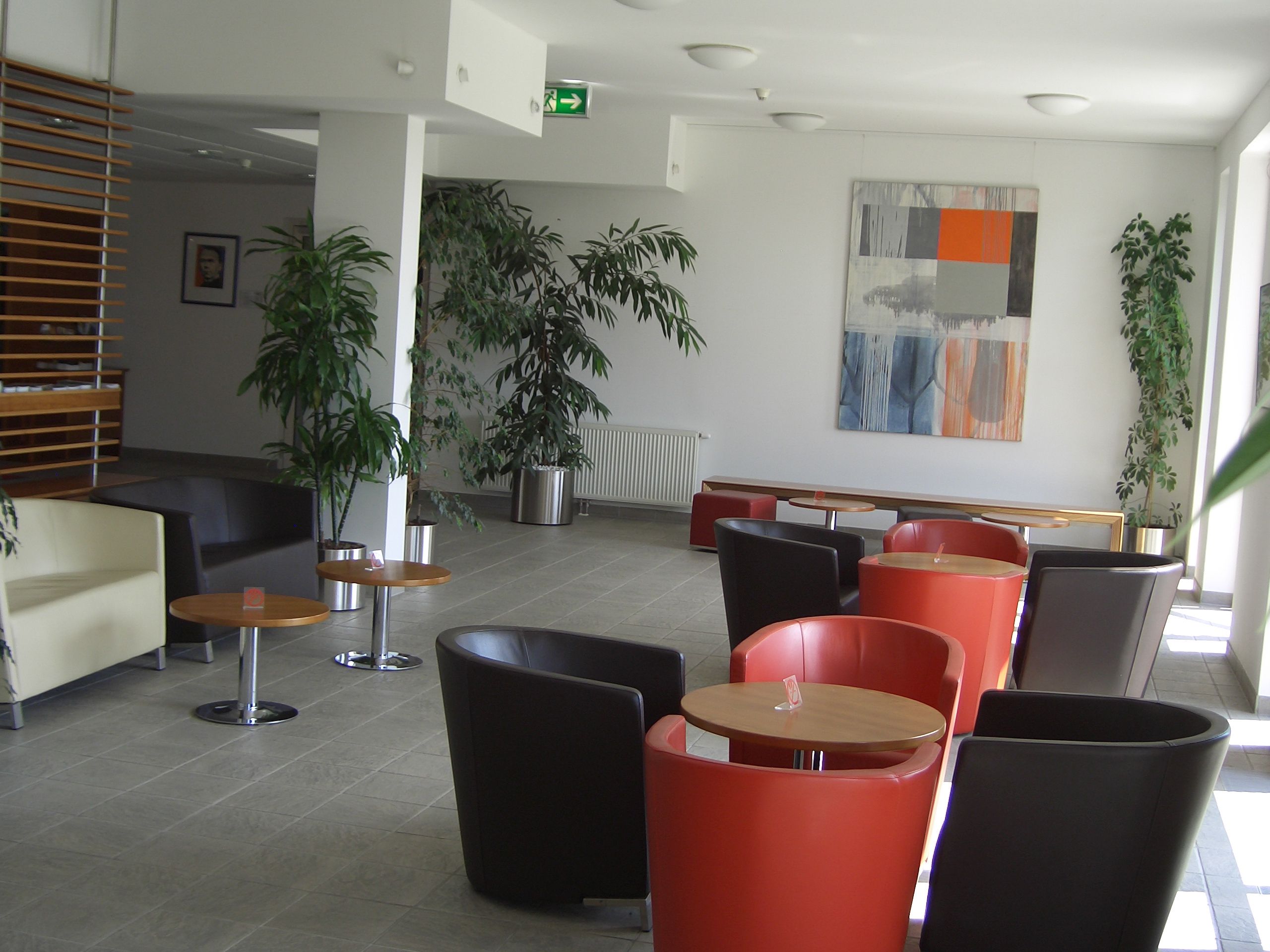 Moderner Aufenthaltsraum mit bunten Sesseln und Pflanzen.