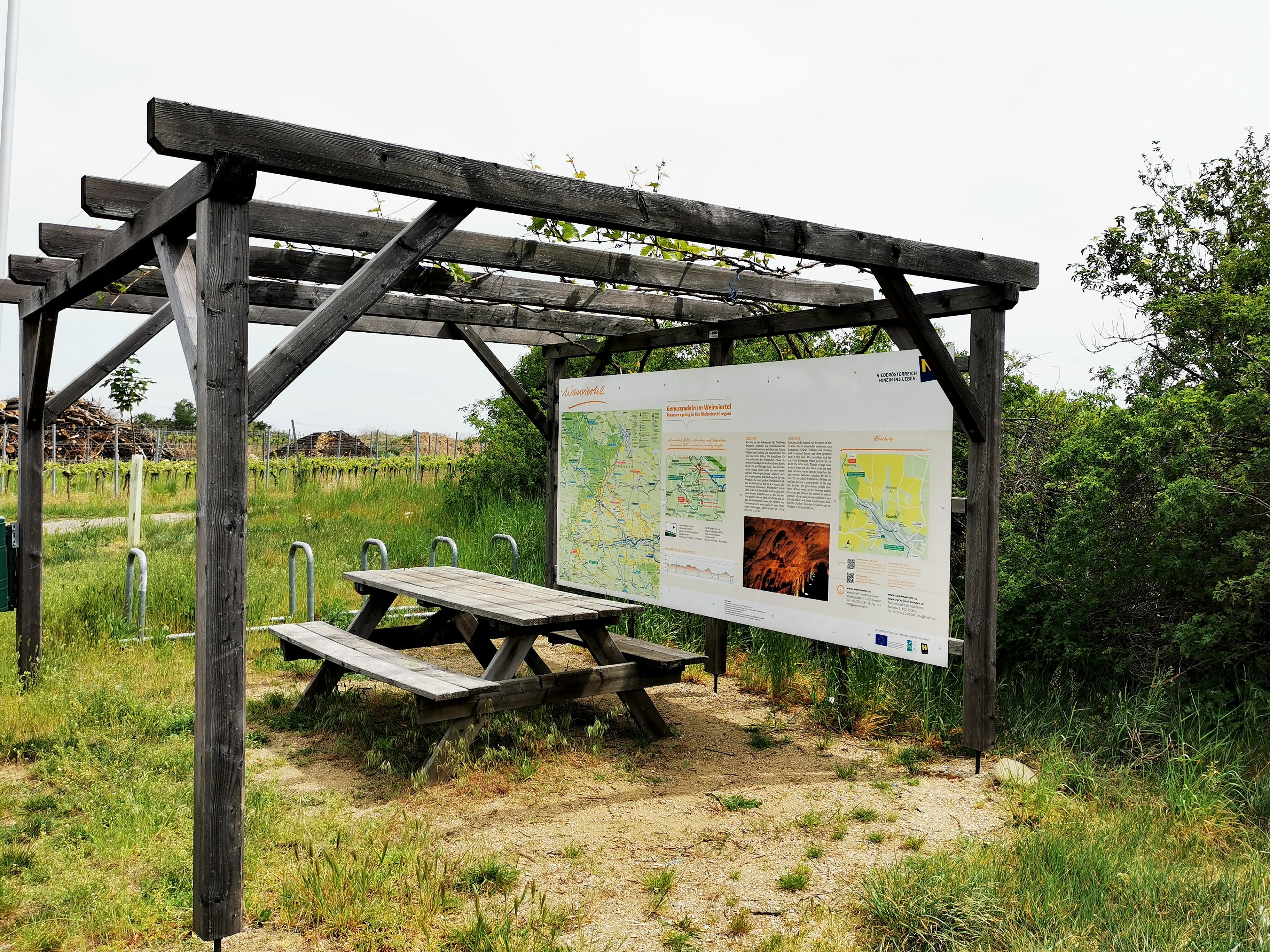 Radlerrastplatz mit Holztisch und Infotafel an der Weinstraße im Weinviertel.