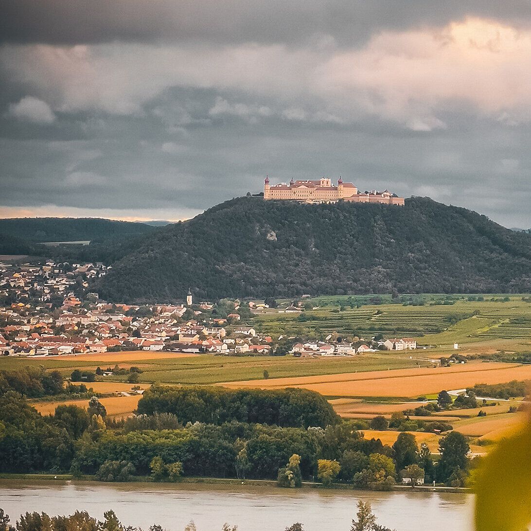 Die sanften Hügel und das glitzernde Wasser der Donau umrahmen das majestätische Stift Göttweig, das hoch oben auf dem Berg thront. Diese malerische Landschaft lädt dazu ein, die Seele baumeln zu lassen und die Schönheit der Natur zu genießen.