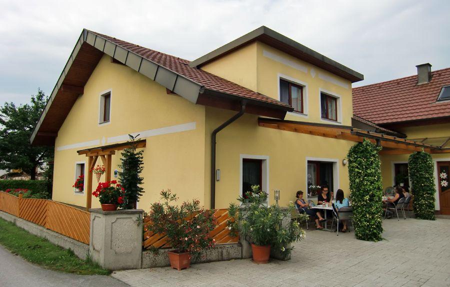 Gelbes Haus mit Terrasse und Menschen, die draußen sitzen.