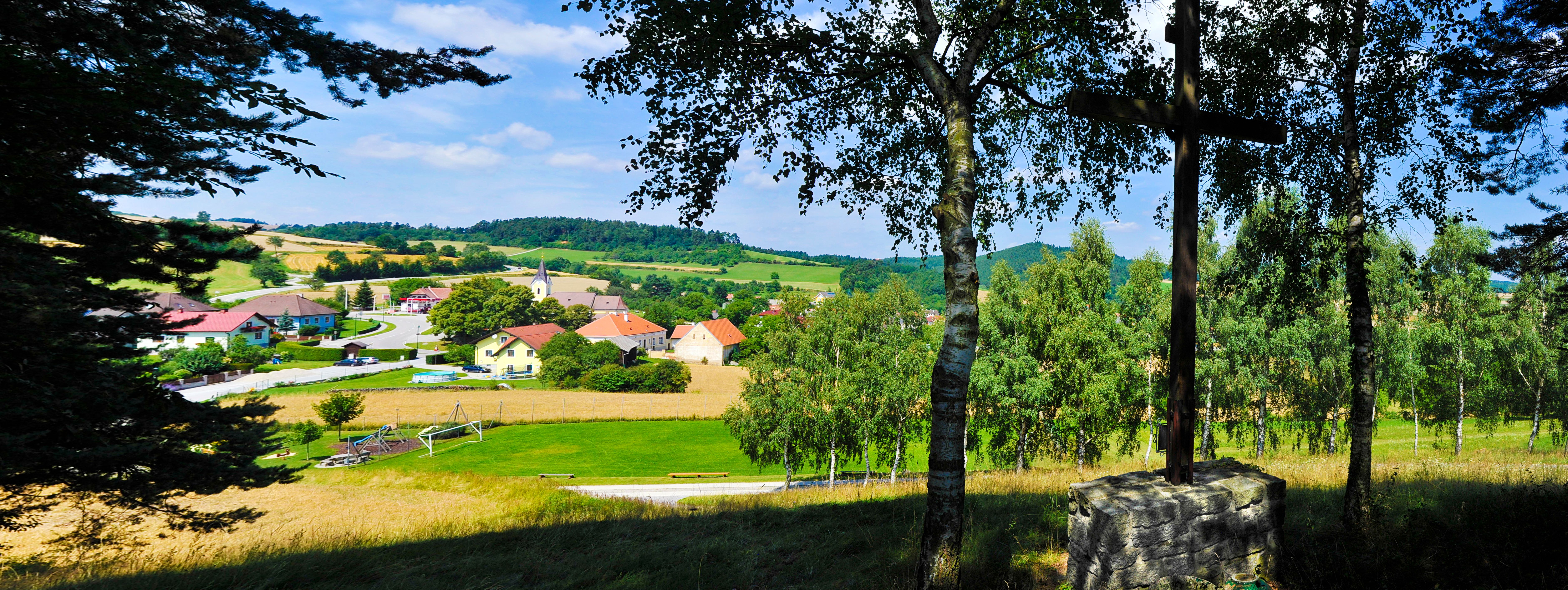 Blick auf eine ländliche Gemeinde mit Kirche und Häusern, umgeben von Feldern und Bäumen.