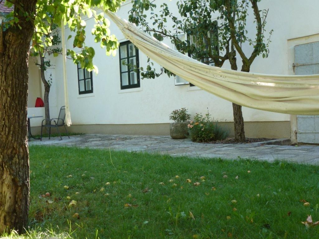 Innenhof mit Hängematte, Bäumen und Rasenfläche.