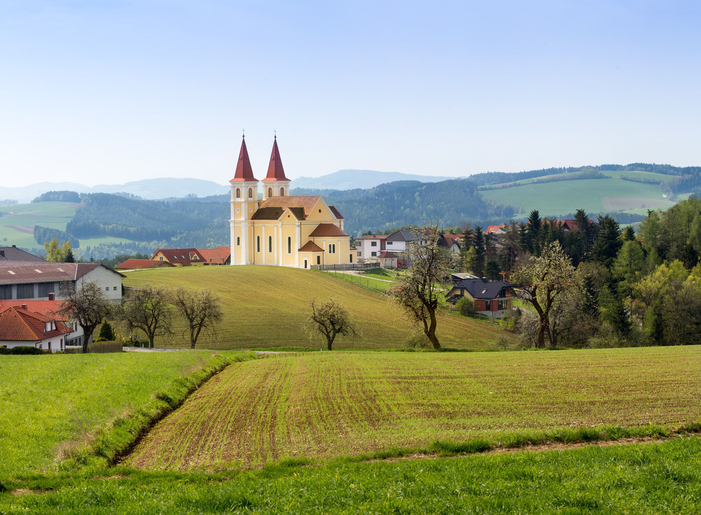 Wallfahrtskirche Maria Schnee auf einem Hügel in ländlicher Umgebung mit grünen Feldern und Bäumen.