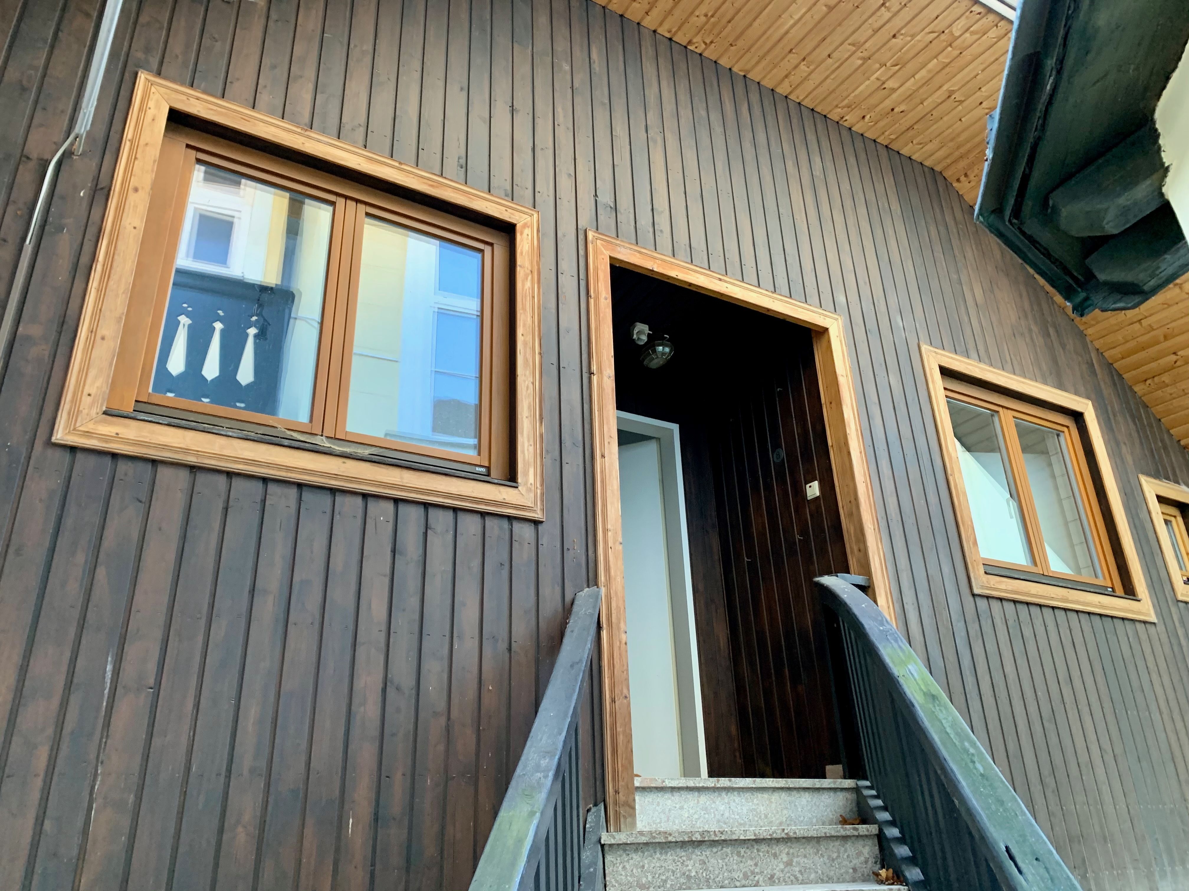 Nahaufnahme einer Hausfassade mit Holzwand und Fenstern.