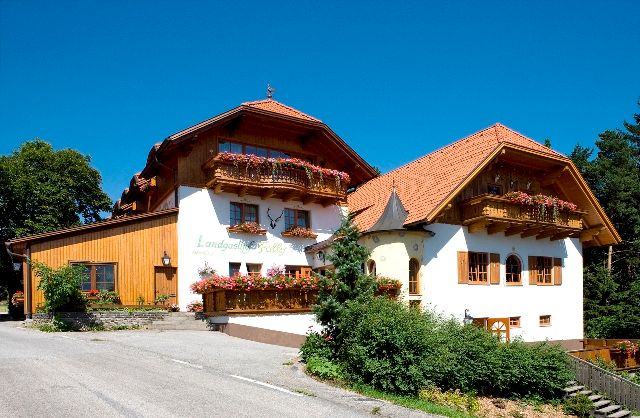 Ein traditioneller Landgasthof mit Holzfassade und Blumenkästen unter blauem Himmel.