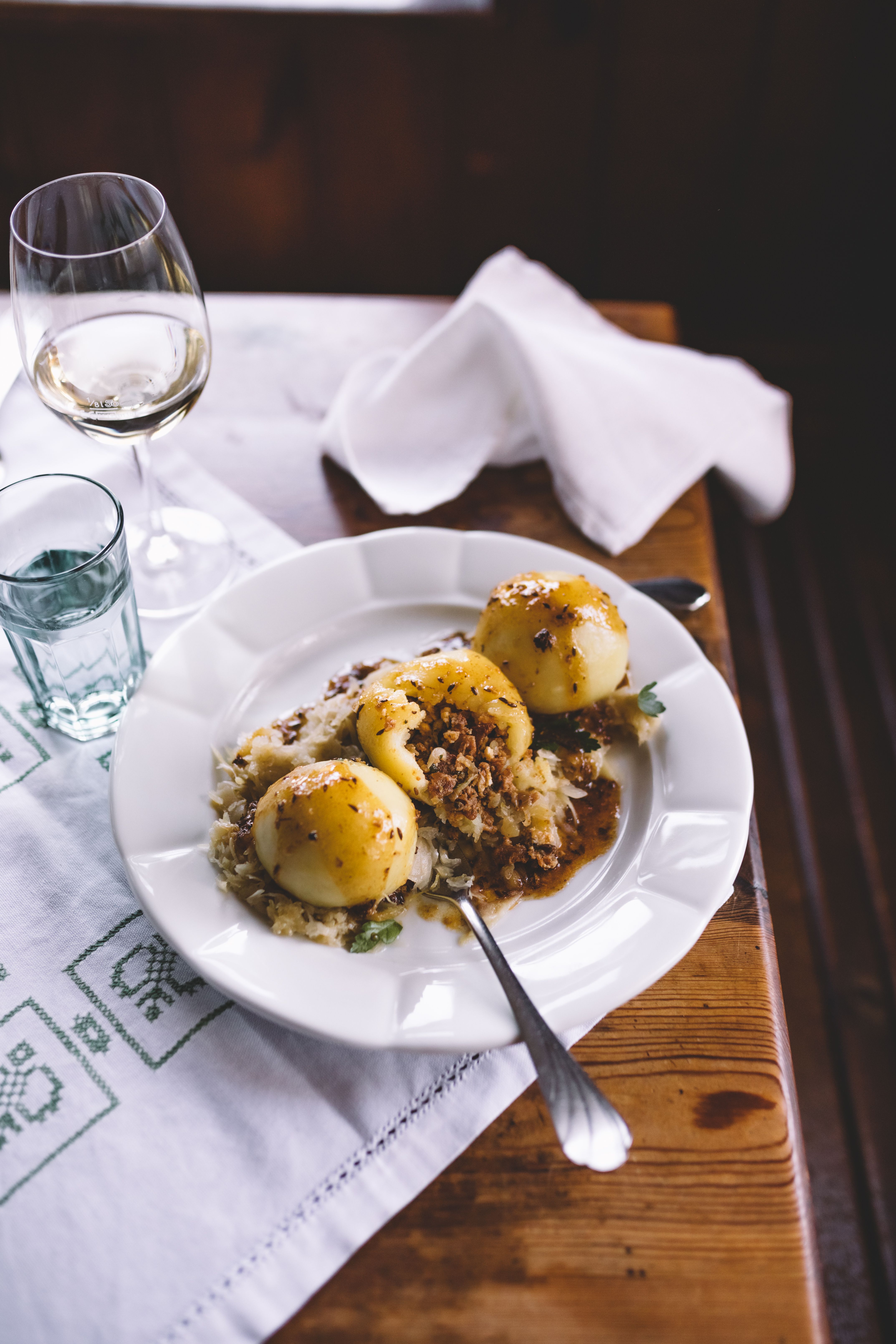 Ein Dessertteller mit einem Nougat-Törtchen, Hollereis, Beeren und einem Löffel auf einem Holztisch.