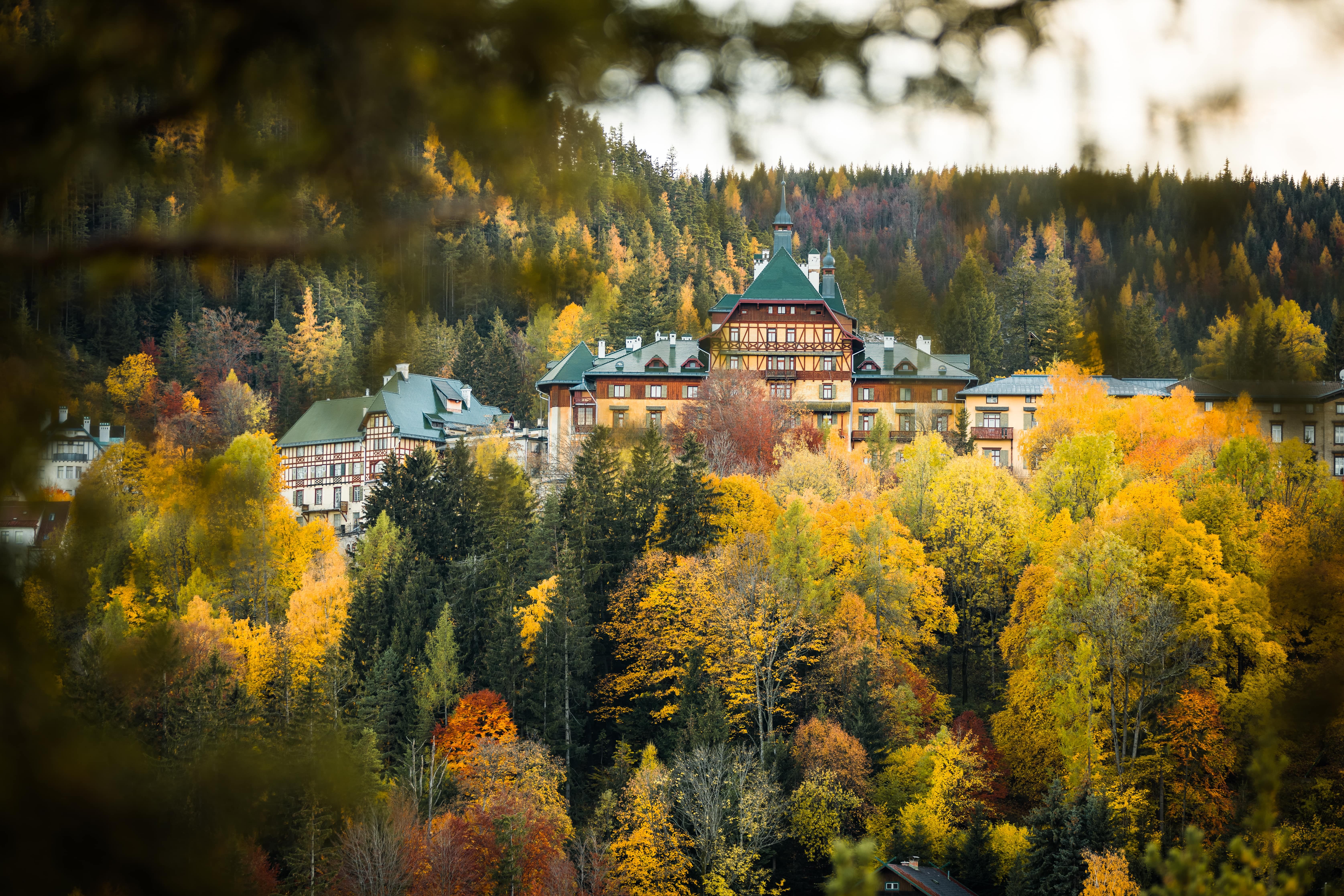 Südbahnhotel Semmering im Herbst, umgeben von buntem Laubwald.