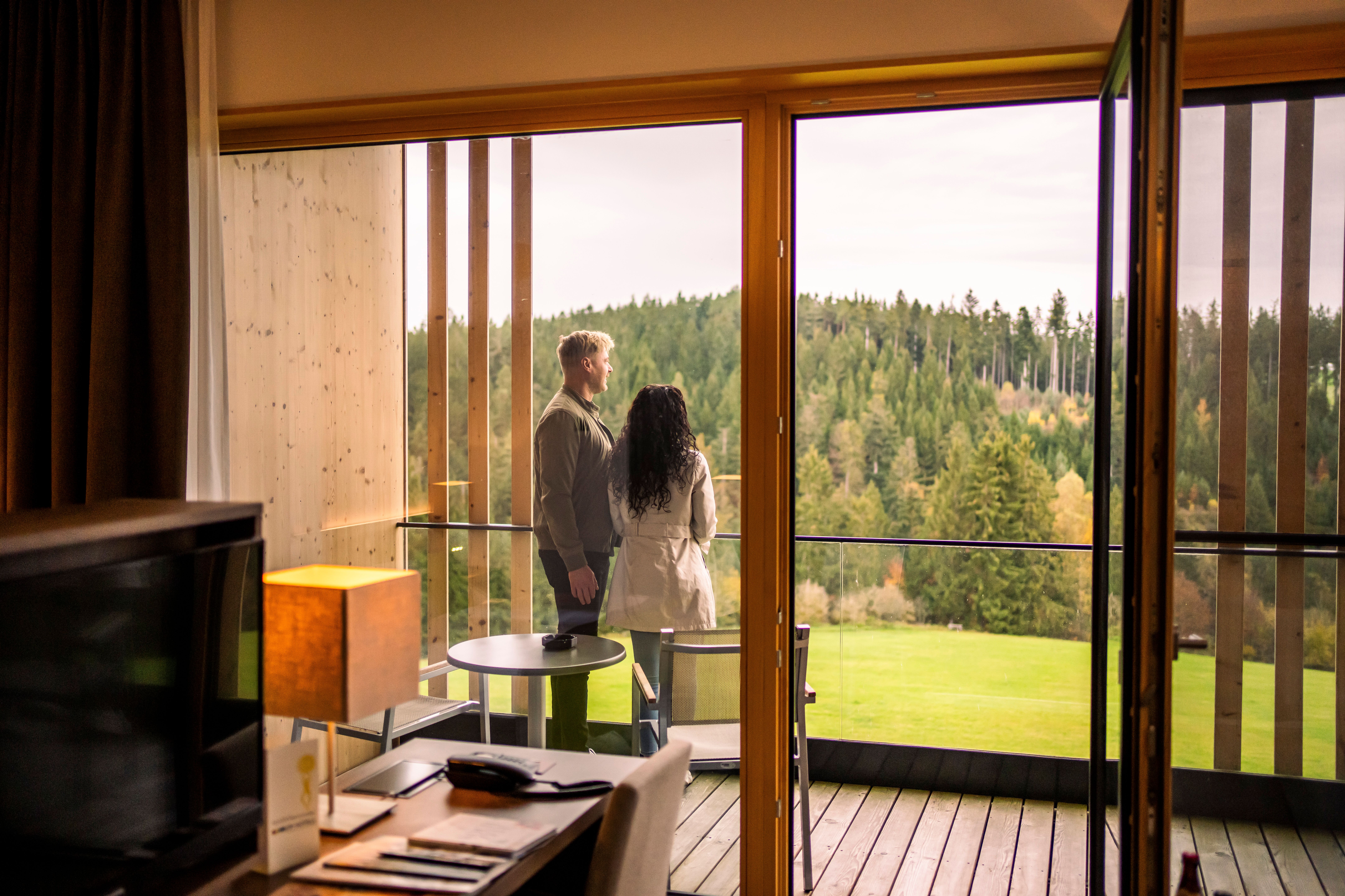 Hotel Schwarz Alm Zwettl mit Naturteich und Liegestühlen, umgeben von grüner Landschaft.