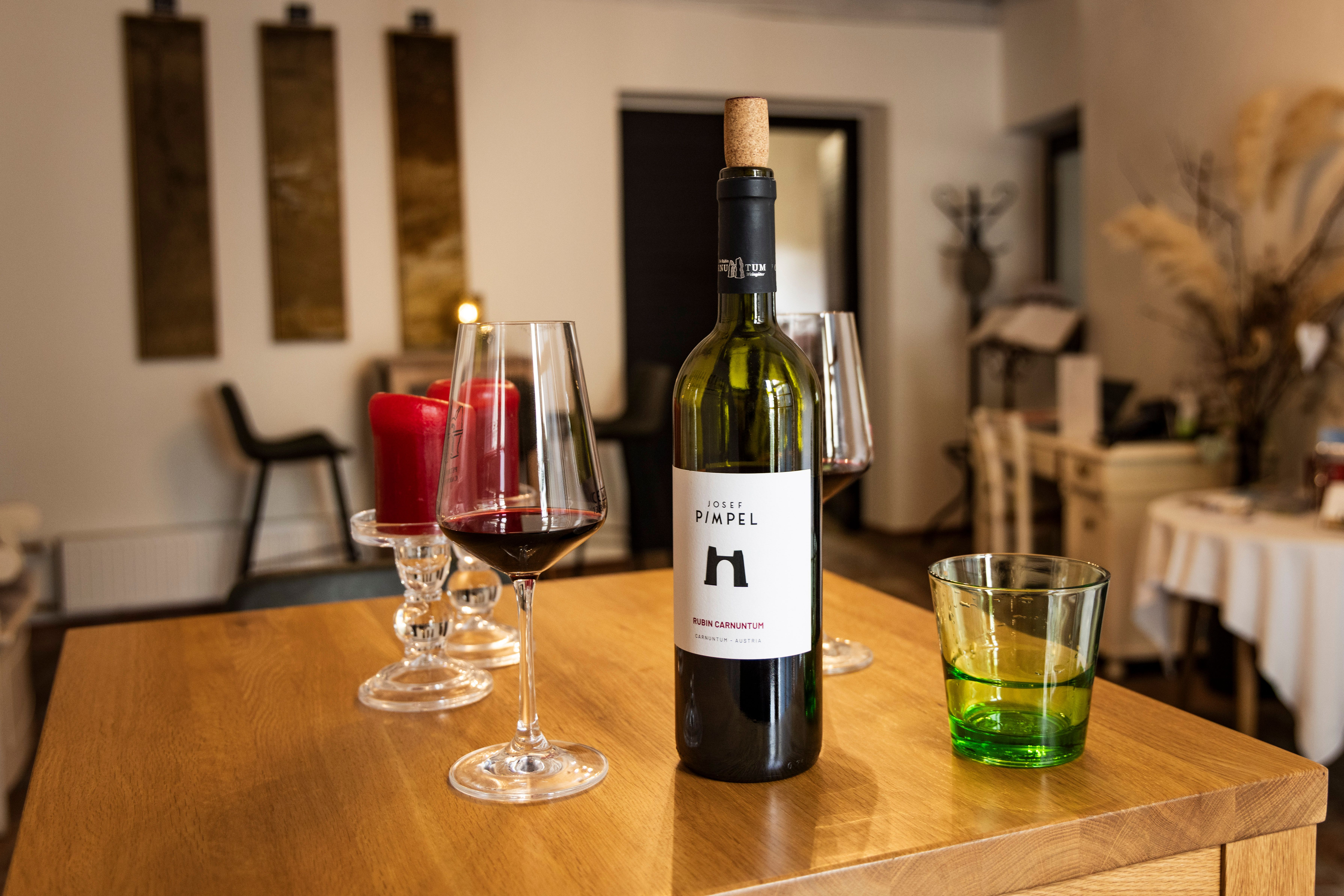 Weingläser mit Rotwein und Weinflasche im Verkostungsraum des Weinguts