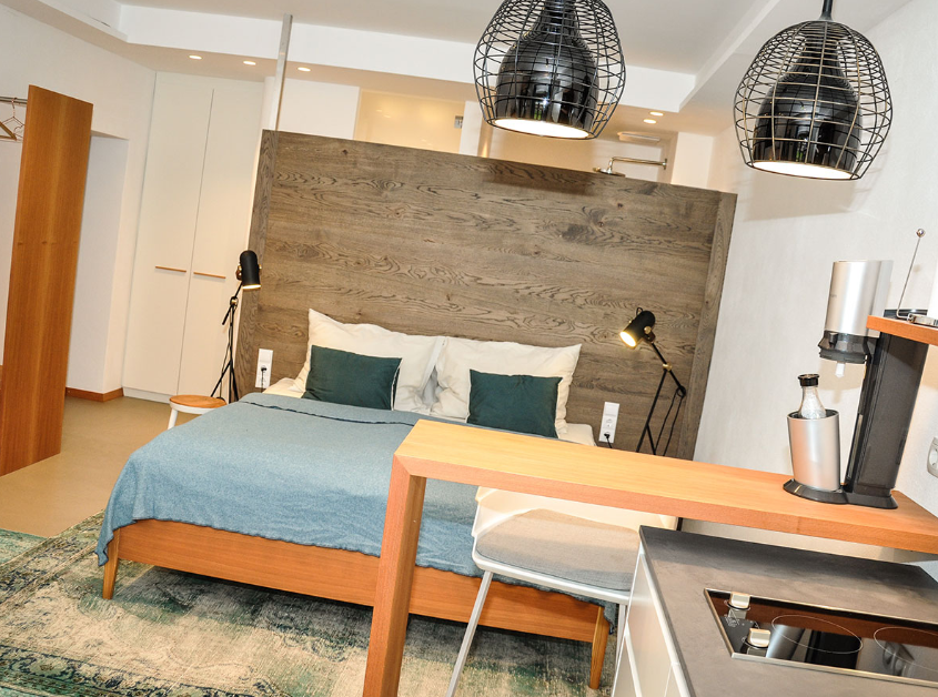 Modernes Studio-Apartment mit Bett, Küche und stilvoller Beleuchtung.