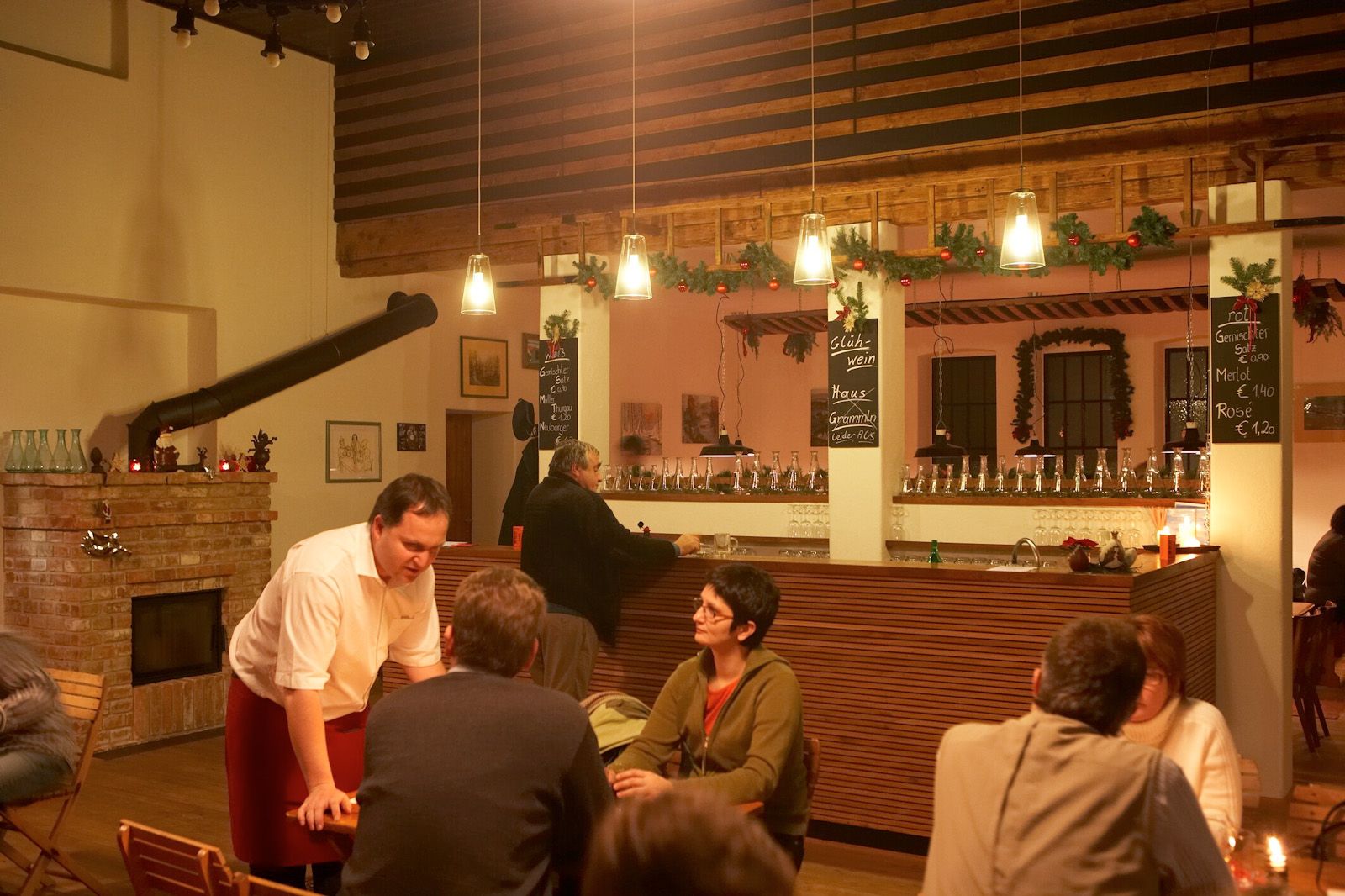 Innenansicht eines gemütlichen Lokals mit Bar und Gästen.