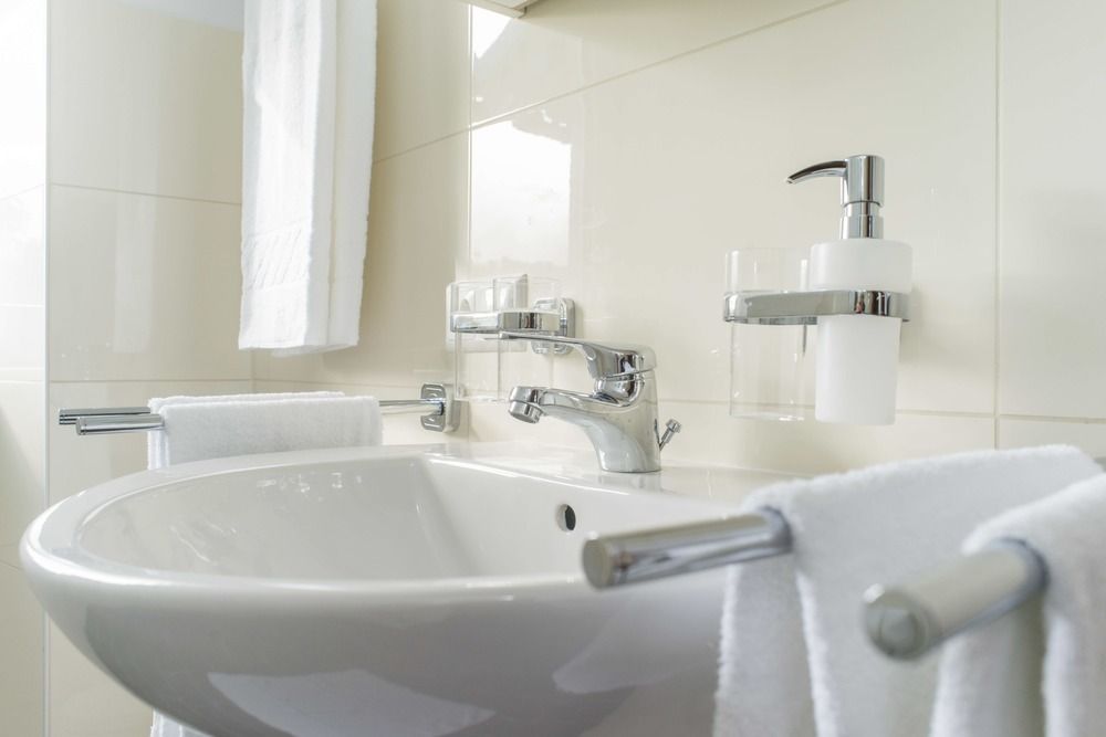 Modernes Badezimmer mit Waschbecken, Handtüchern und Seifenspender.