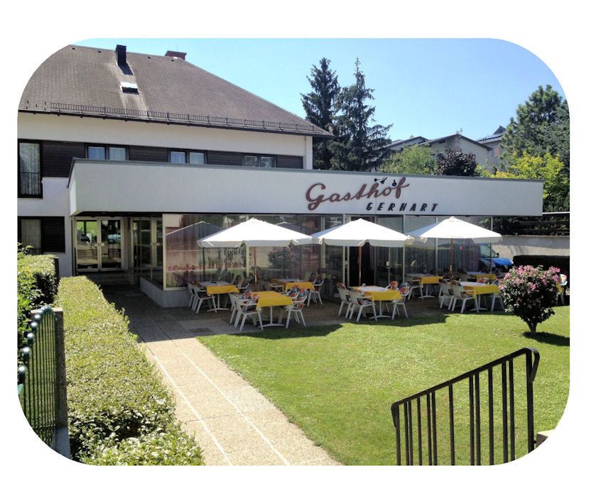 Außenansicht des Gasthofs Gerhart mit Terrasse und Sonnenschirmen.