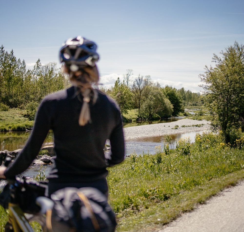Ein malerischer Radweg schlängelt sich entlang eines sanft plätschernden Baches, umgeben von üppigem Grün und blühenden Wiesen. Die klare Luft und die strahlende Sonne laden dazu ein, die Schönheit der Natur zu genießen und die Seele baumeln zu lassen.
