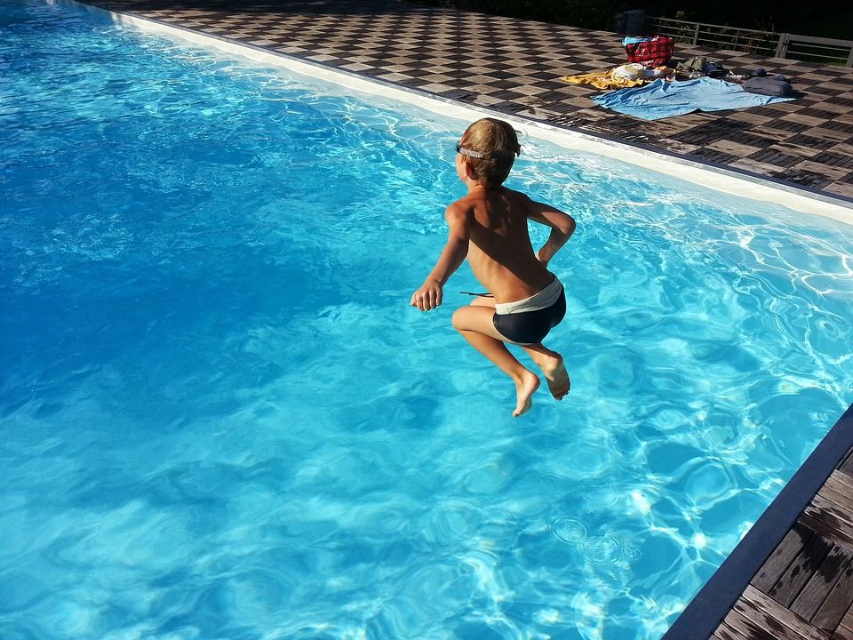 Ein Kind springt in einen Pool mit klarem, blauem Wasser.