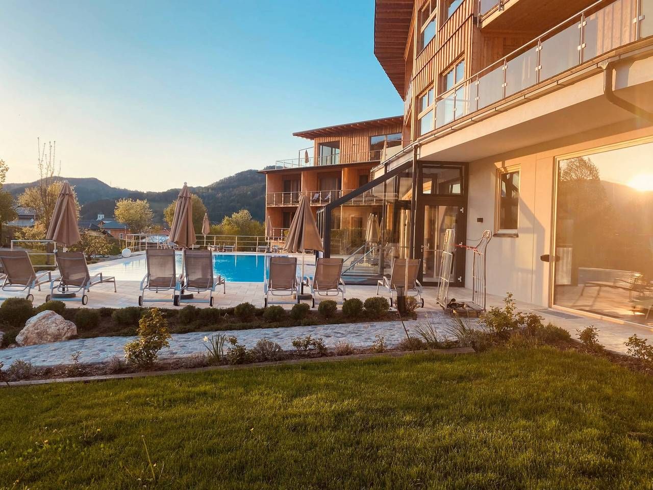 Außenbereich des Naturhotel Molzbachhof mit Pool und Liegestühlen bei Sonnenuntergang.