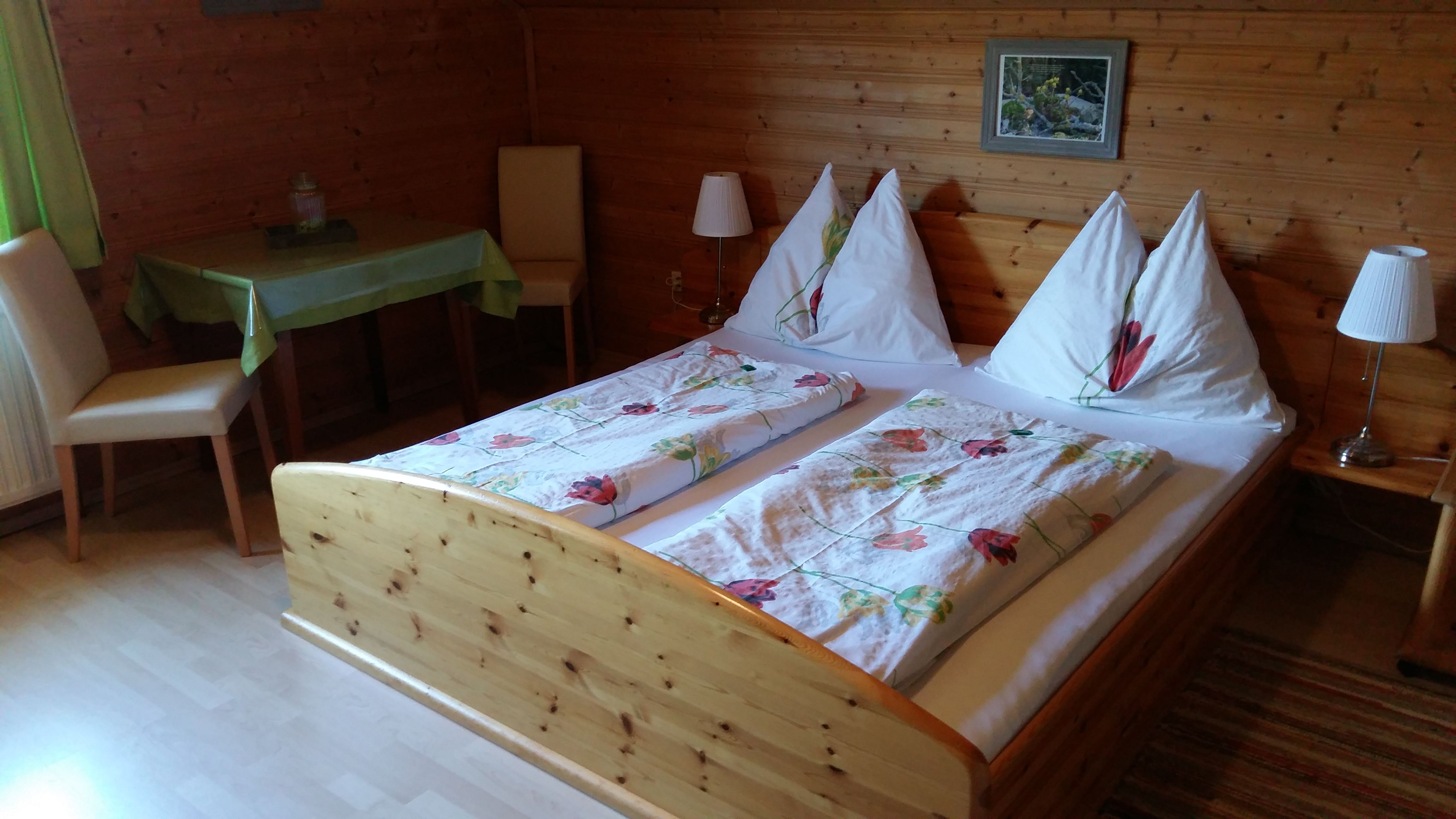 Gemütliches Zimmer mit Holzwänden, Doppelbett und Tisch im Bauernhof Wachabauer.