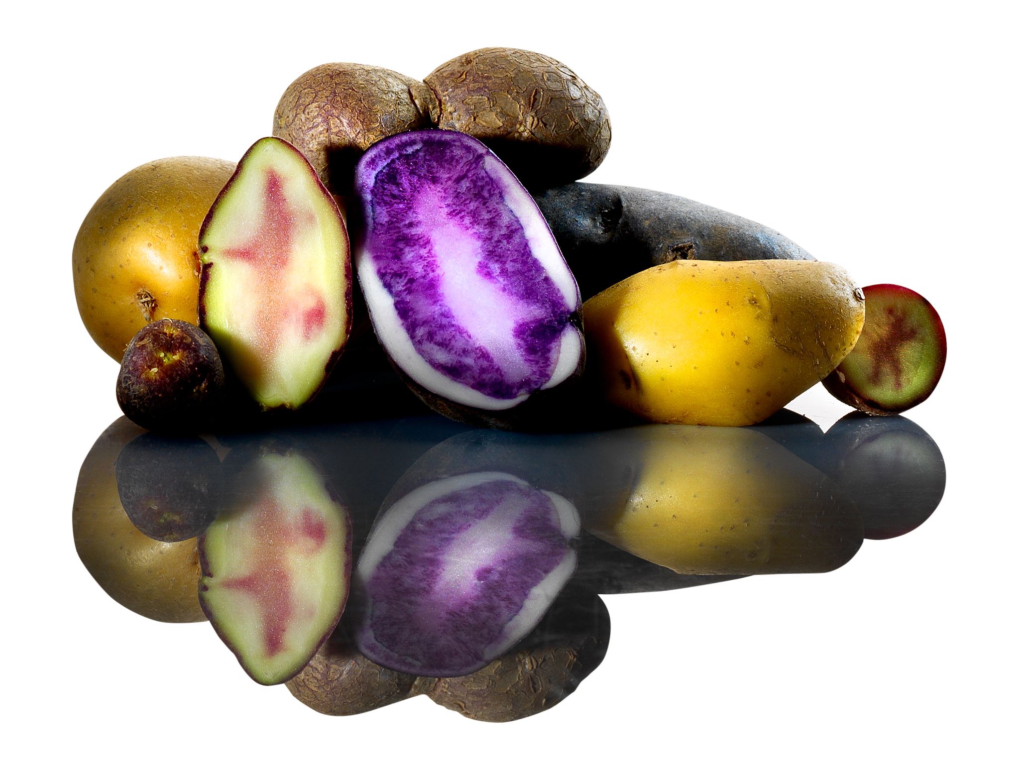 Verschiedene Kartoffelsorten, teils aufgeschnitten, auf spiegelnder Oberfläche.