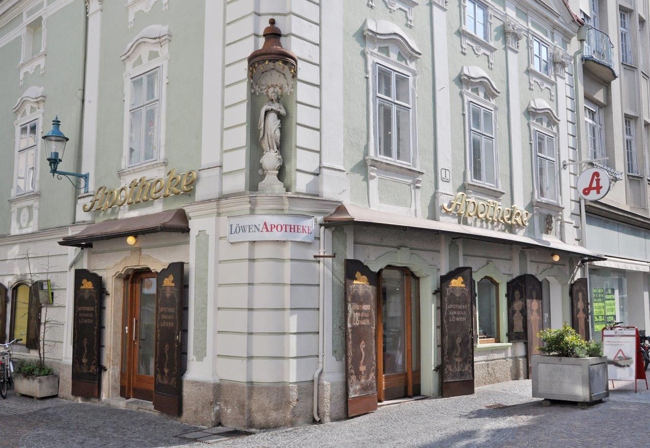Historische Apotheke mit grüner Fassade und goldener Schrift in einer Stadt.