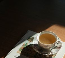 Tasse Kaffee steht auf einem Buch auf einem Tisch im warmen Licht.