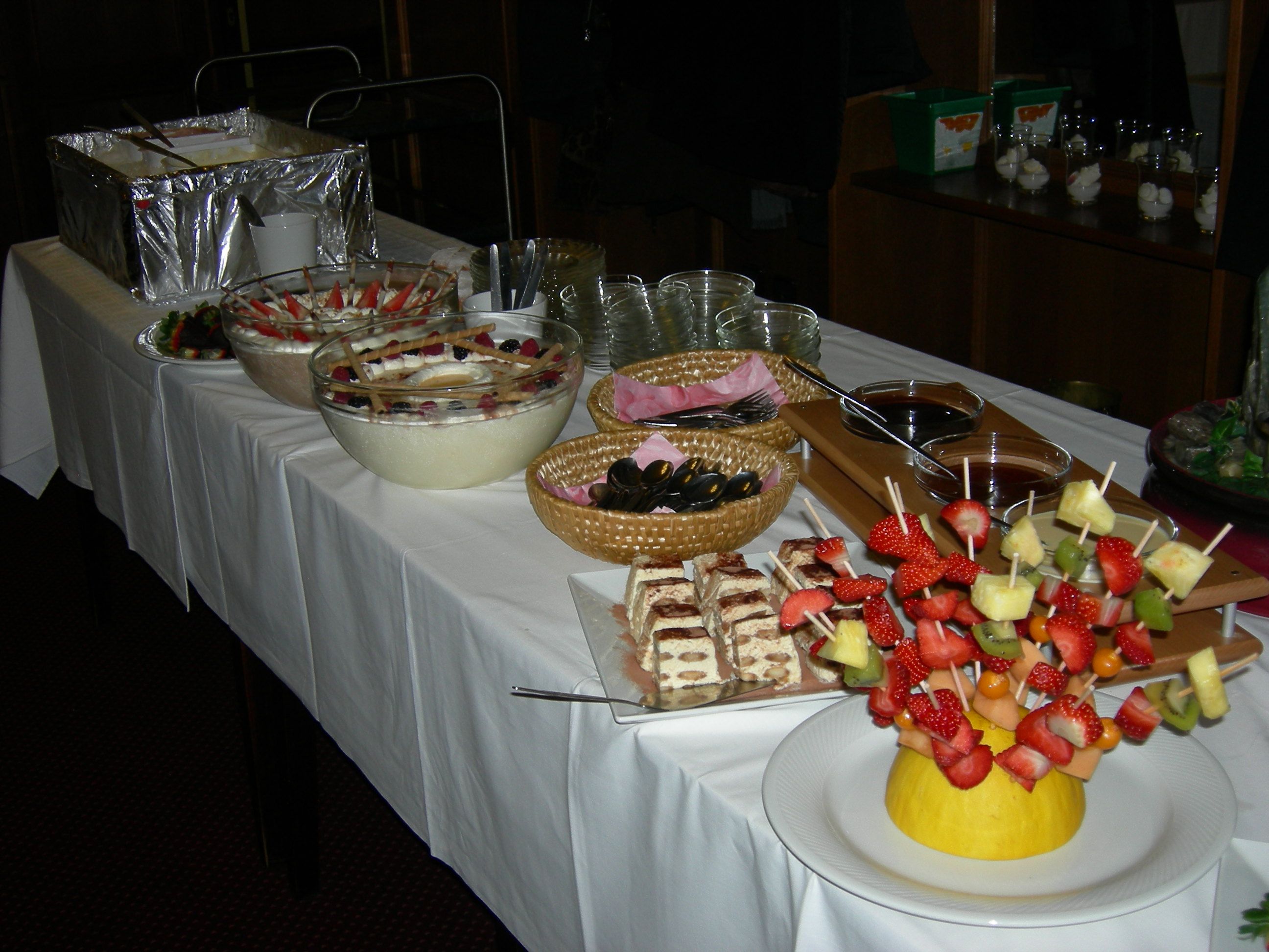 Buffet mit Desserts und Obstspießen auf einem Tisch.