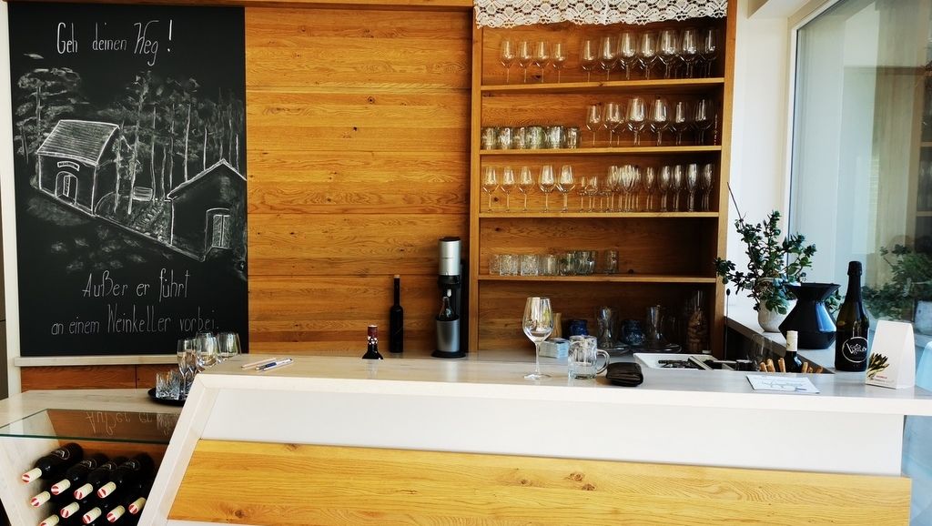 Verkostungsraum mit Holztheke, Weingläsern und Tafel mit Zeichnung.