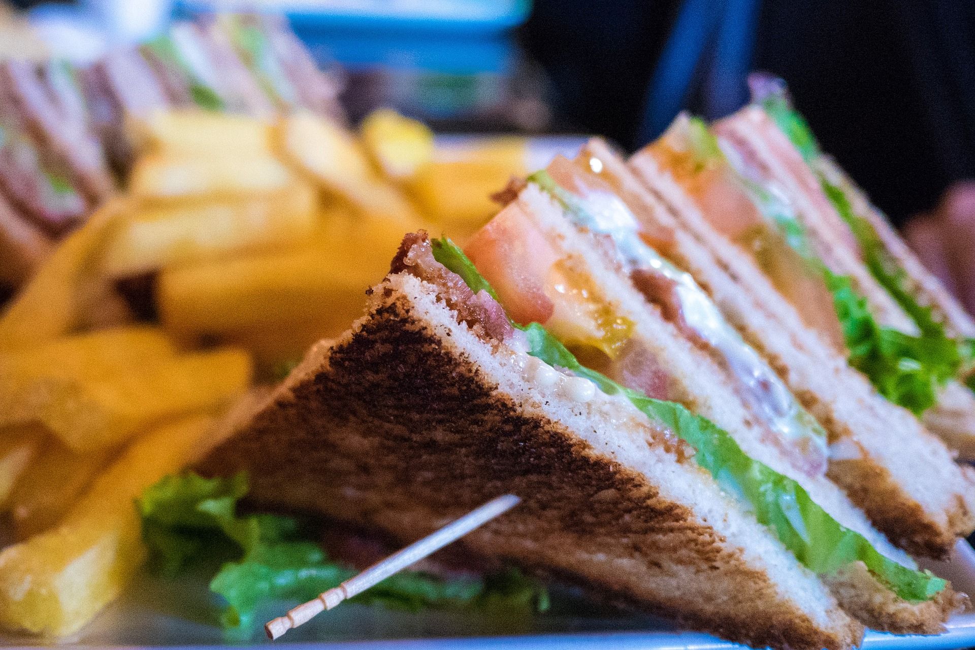 Nahaufnahme von Club Sandwiches mit Pommes Frites im Hintergrund.