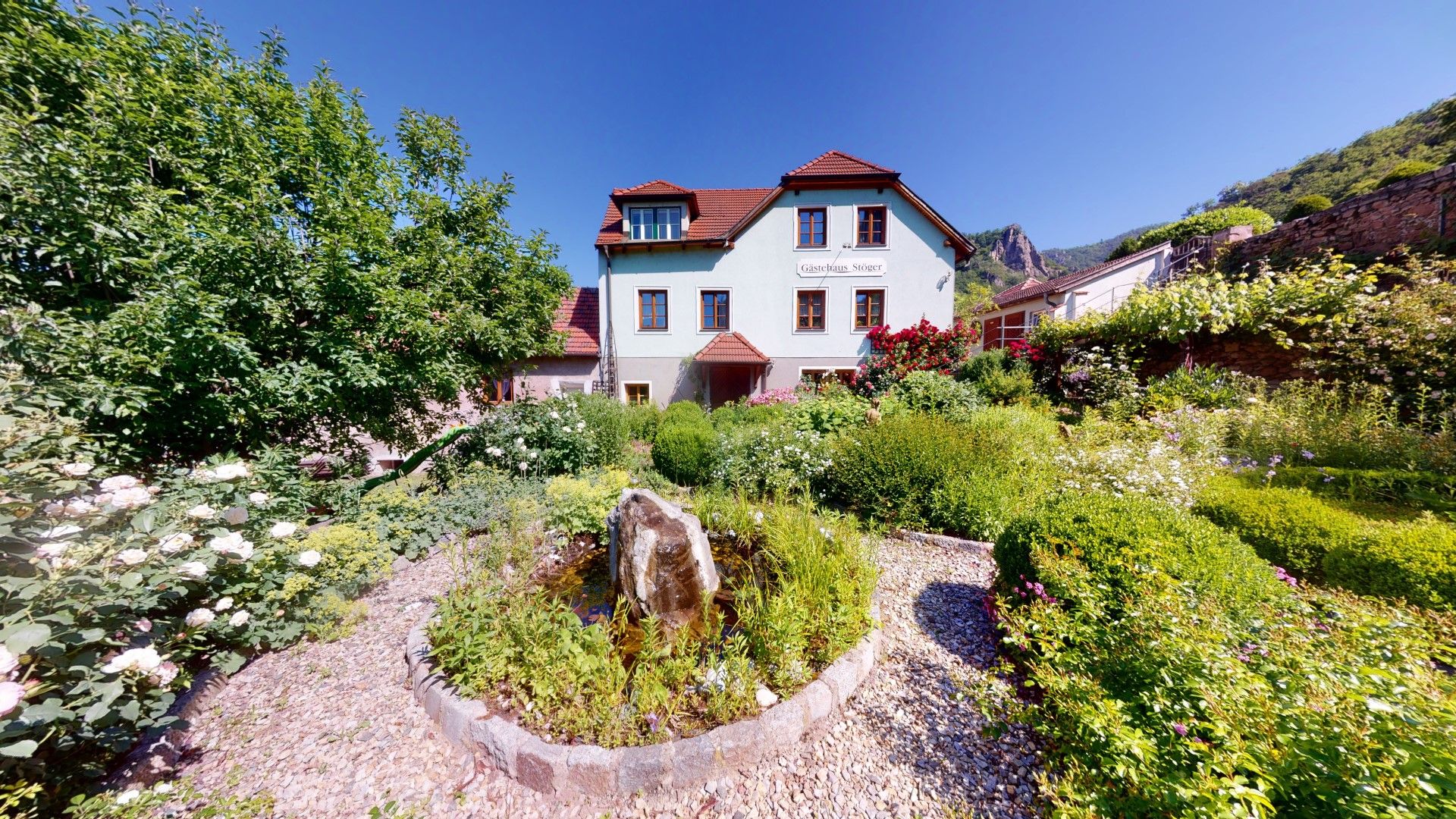 Hellblaues Einfamilienhaus mit Garten davor