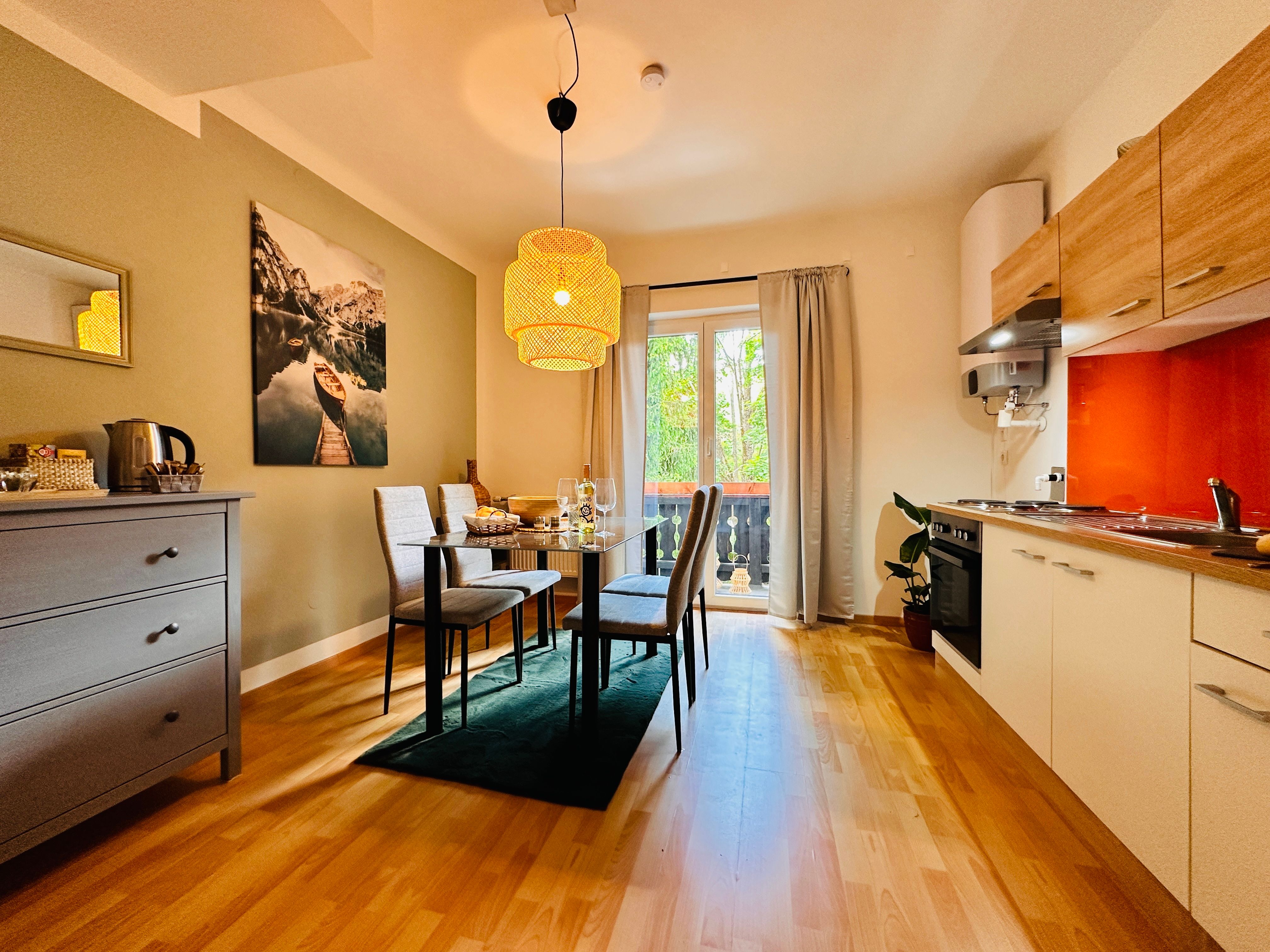 Gemütliches Apartment mit Esstisch, Stühlen, Küchenzeile und Balkon.