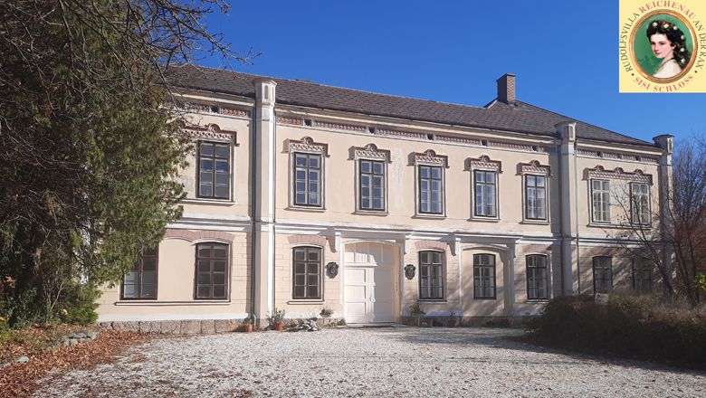 Sisi-Schloss Rudolfsvilla in Reichenau, zweistöckiges Gebäude mit hellem Anstrich und dekorativen Fenstern.