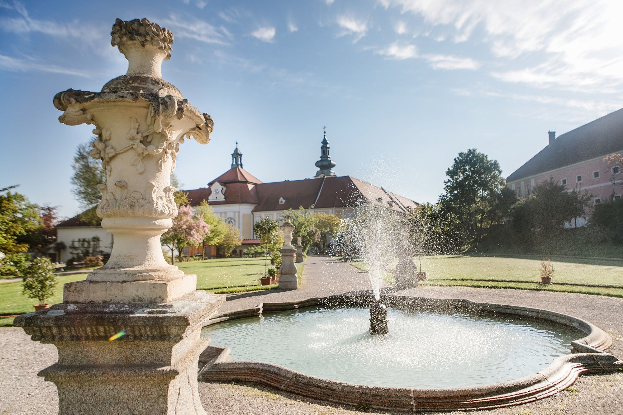 Brunnen im Garten des Stifts Seitenstetten mit barocker Architektur im Hintergrund.