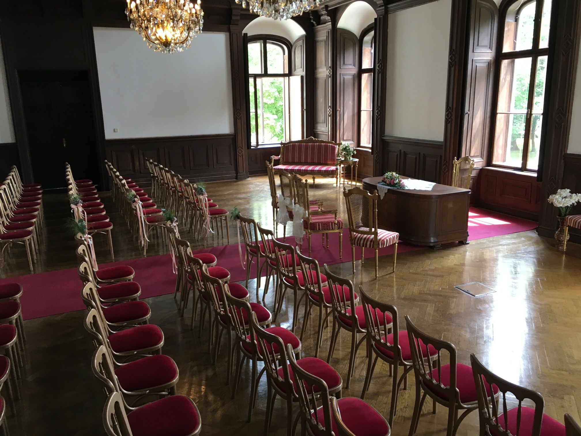 Saal im Schloss mit roten Stühlen und einem roten Teppich 
