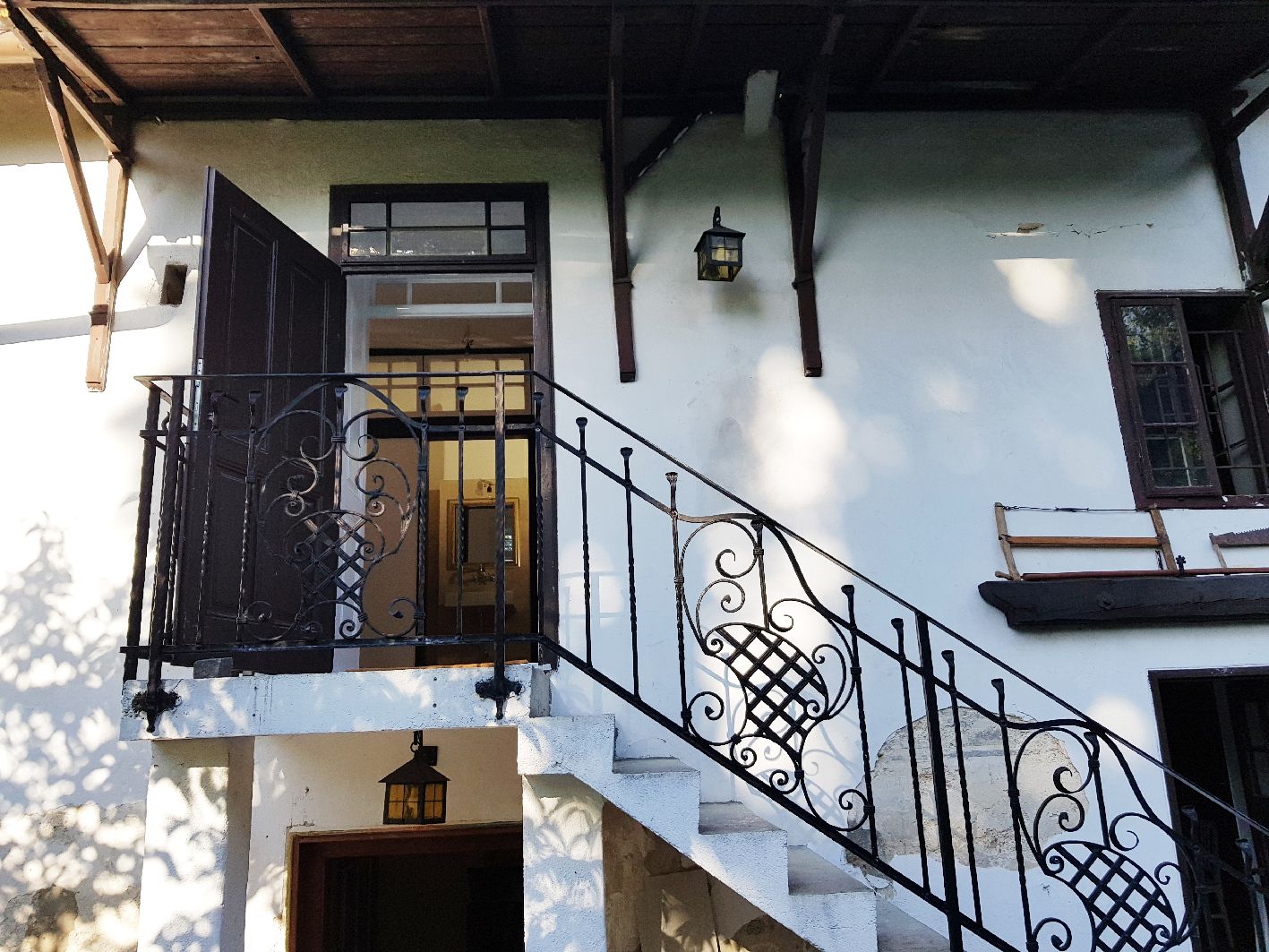 Eingangsbereich eines Hauses mit Treppe und schmiedeeisernem Geländer.