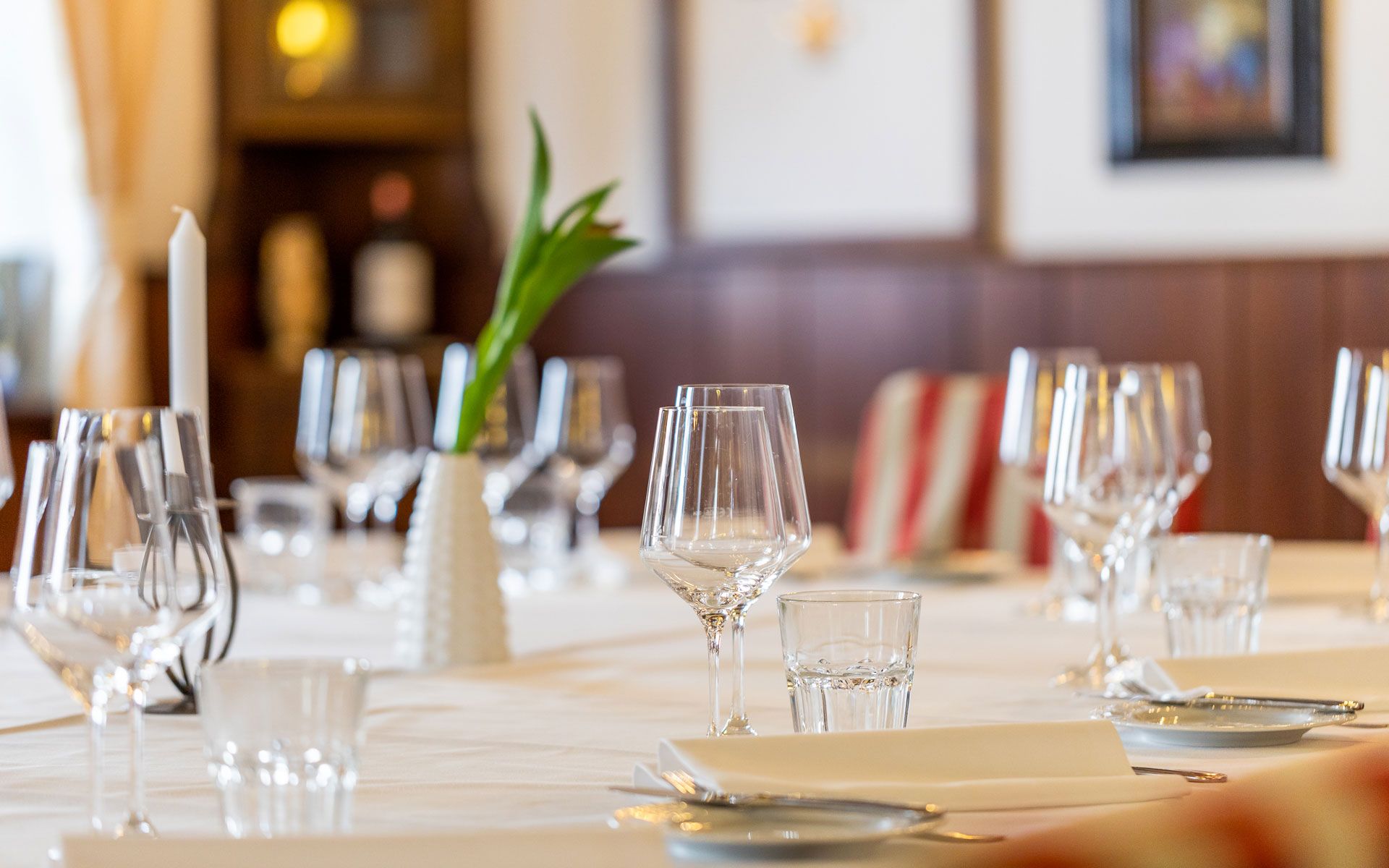 Eleganter Tisch im Hotel Post mit Weingläsern, Kerze und Blumenvase.