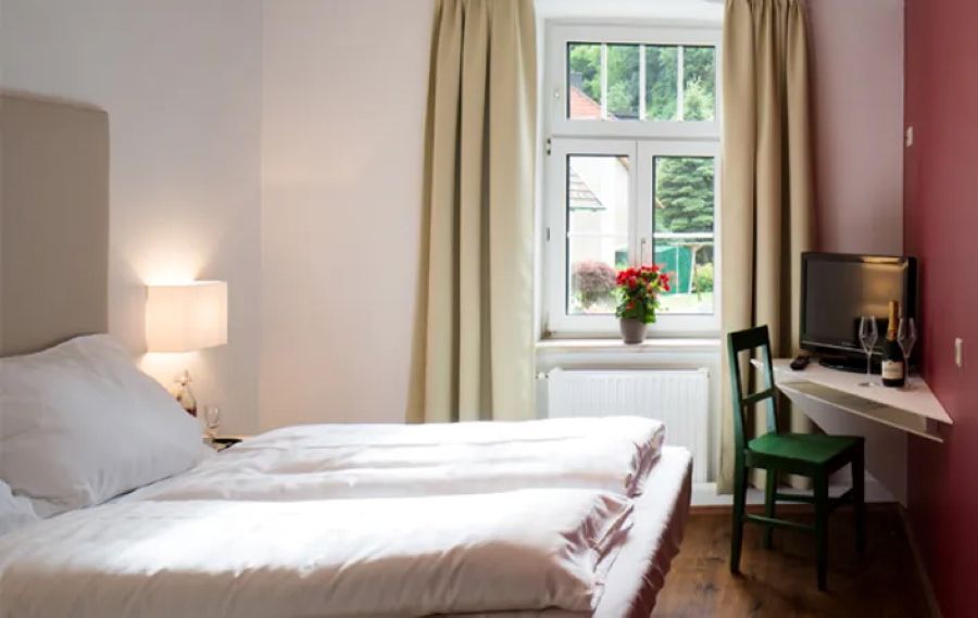 Doppelbett mit Fenster und Tischecke mit Fernseher