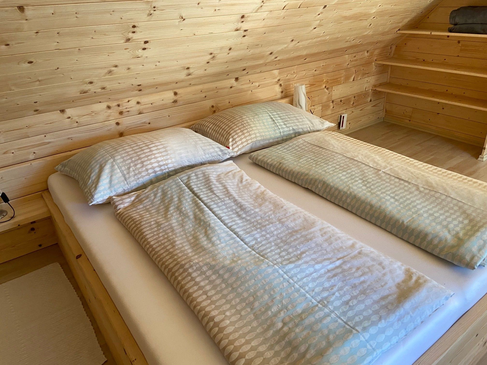 Doppelbett in einem Zimmer mit Holzverkleidung.
