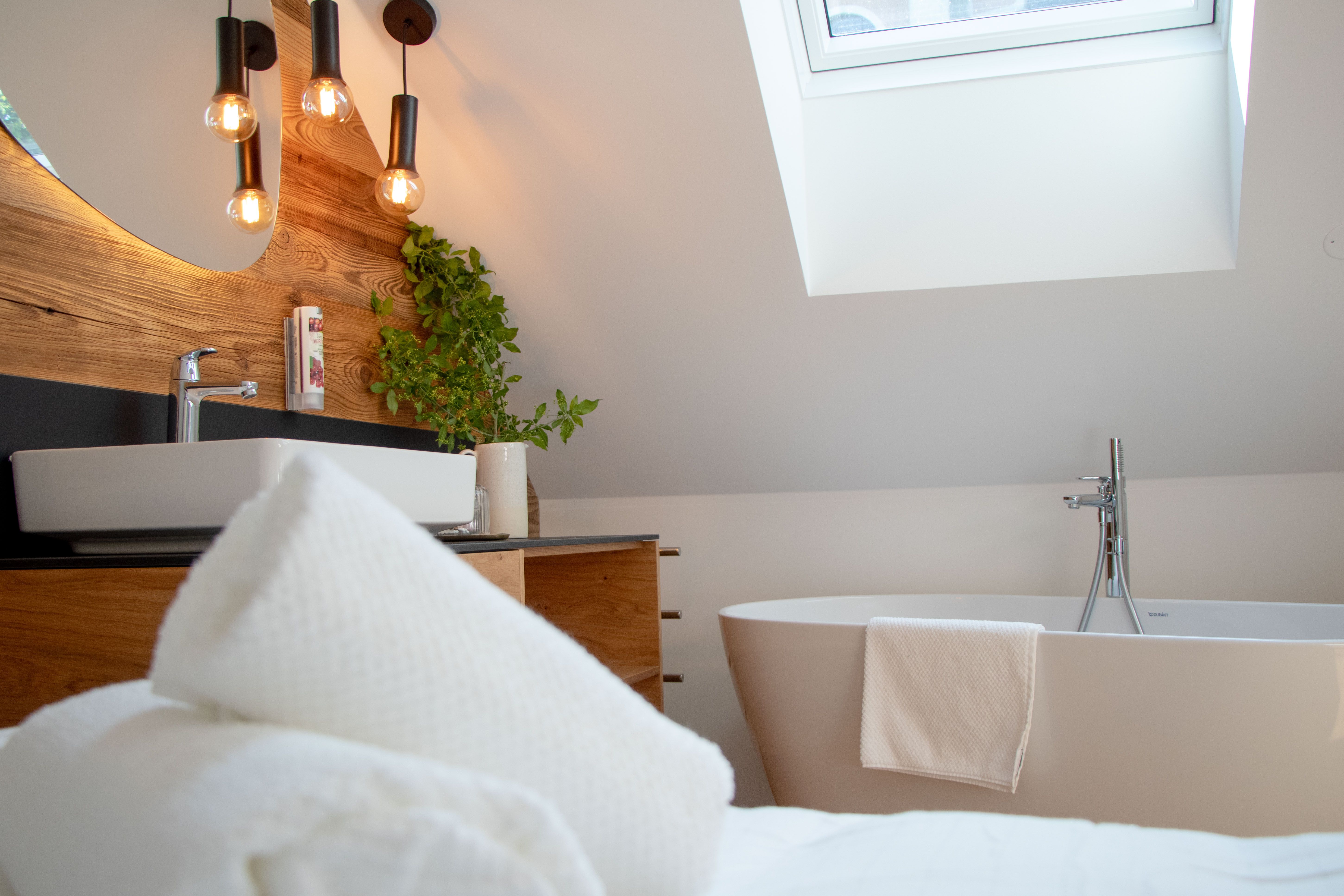 Modernes Badezimmer mit Badewanne, Waschbecken, Pflanzen und Dachfenster.