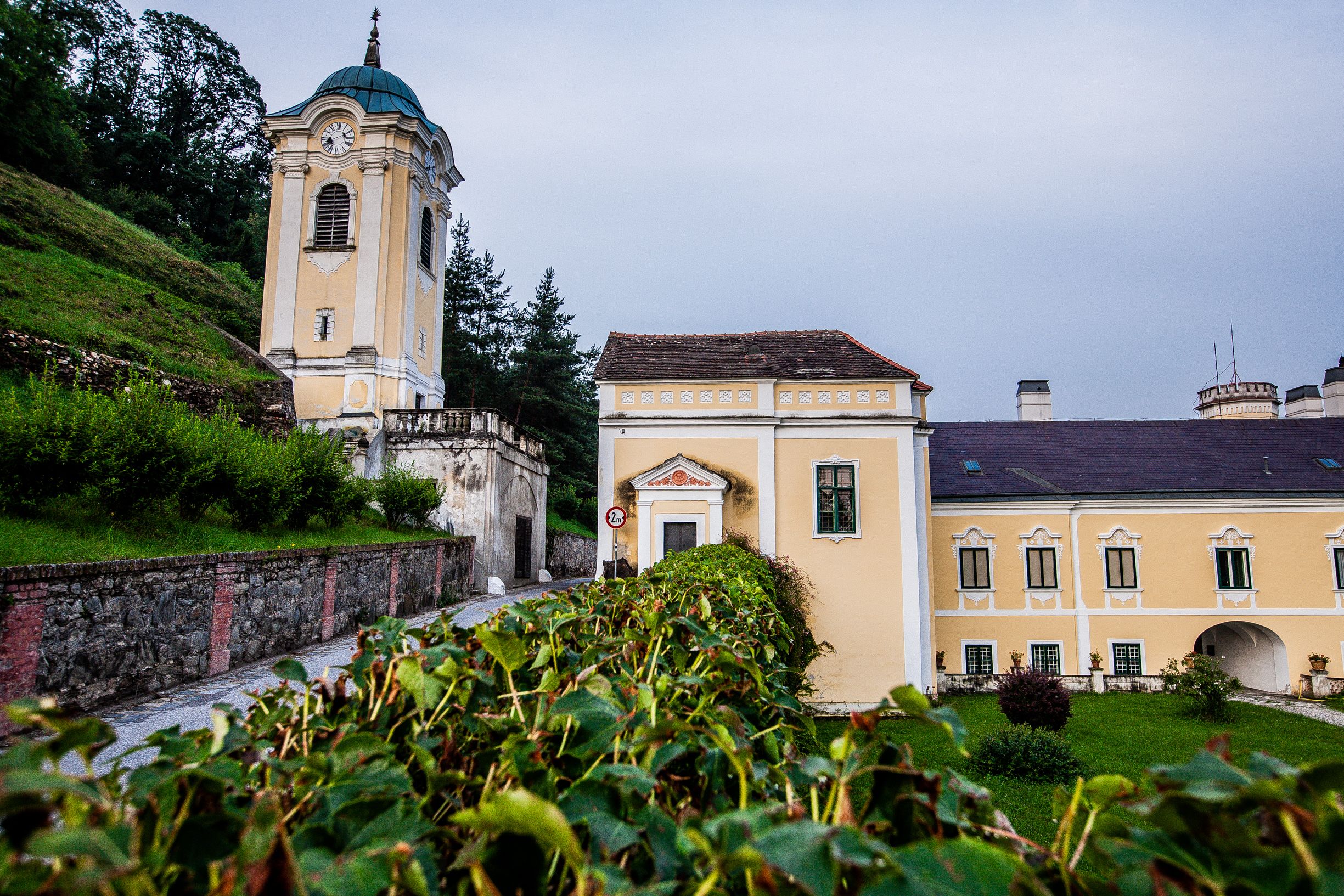 Schloss mit Turm in Bad Erlach, eine Straße führt durch, umgeben von grüner Landschaft.