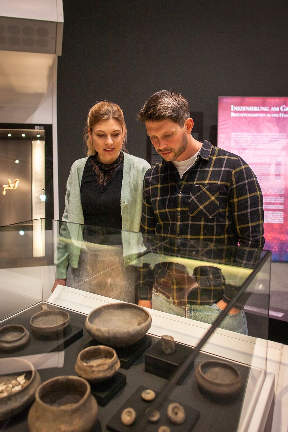 Zwei Personen betrachten Artefakte in einer Glasvitrine im Museum.
