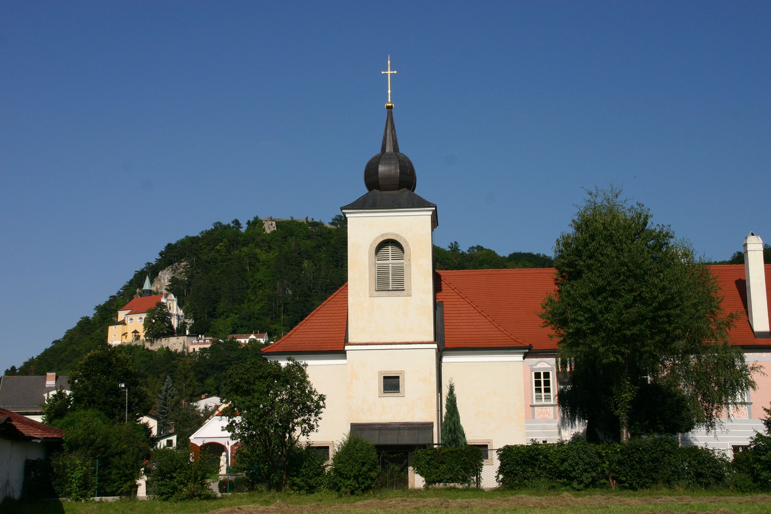 Pfarrhof Pitten mit Kirche und Hügel im Hintergrund.