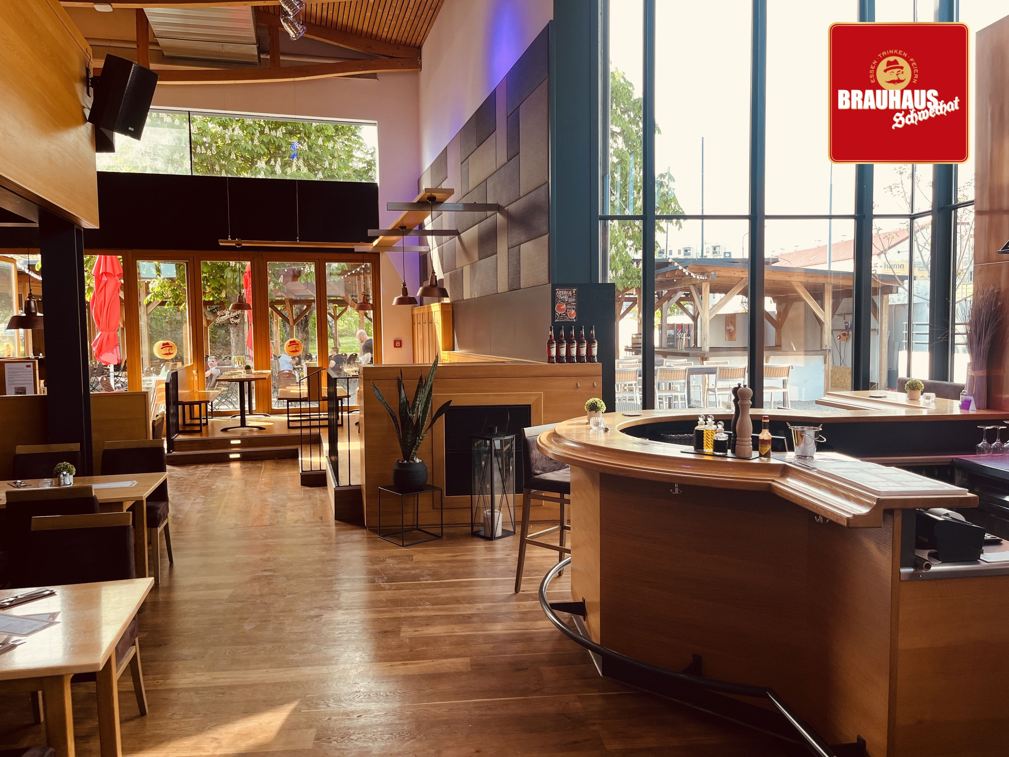 Innenansicht eines modernen Brauhauses mit Holzmöbeln und großen Fenstern.