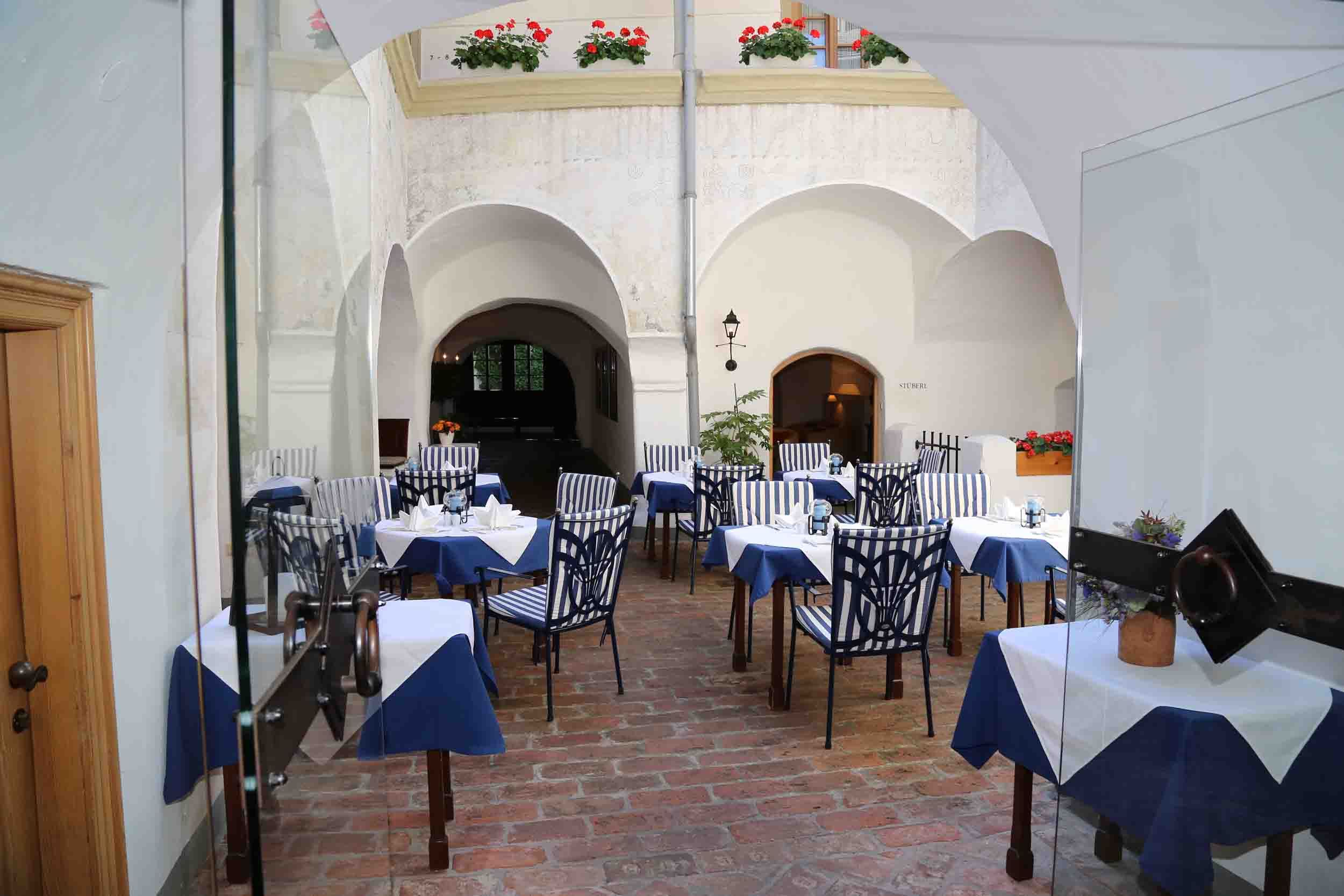 Innenhof eines Restaurants mit gedeckten Tischen und gestreiften Stühlen.