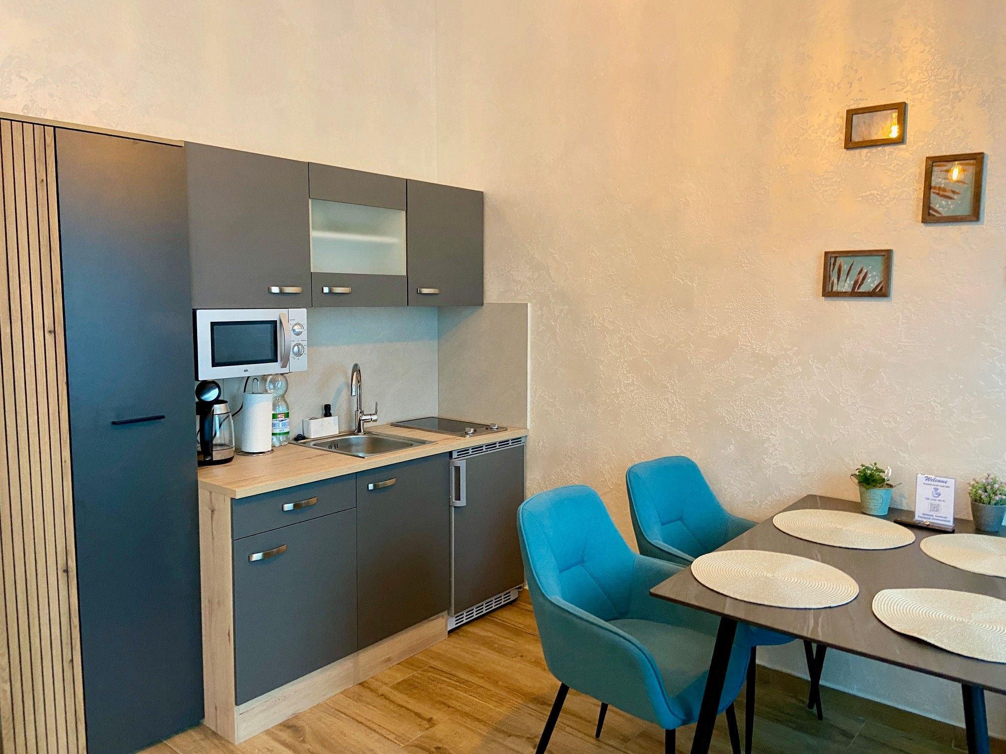 Moderne Küchenzeile mit grauen Schränken und Esstisch mit blauen Stühlen.