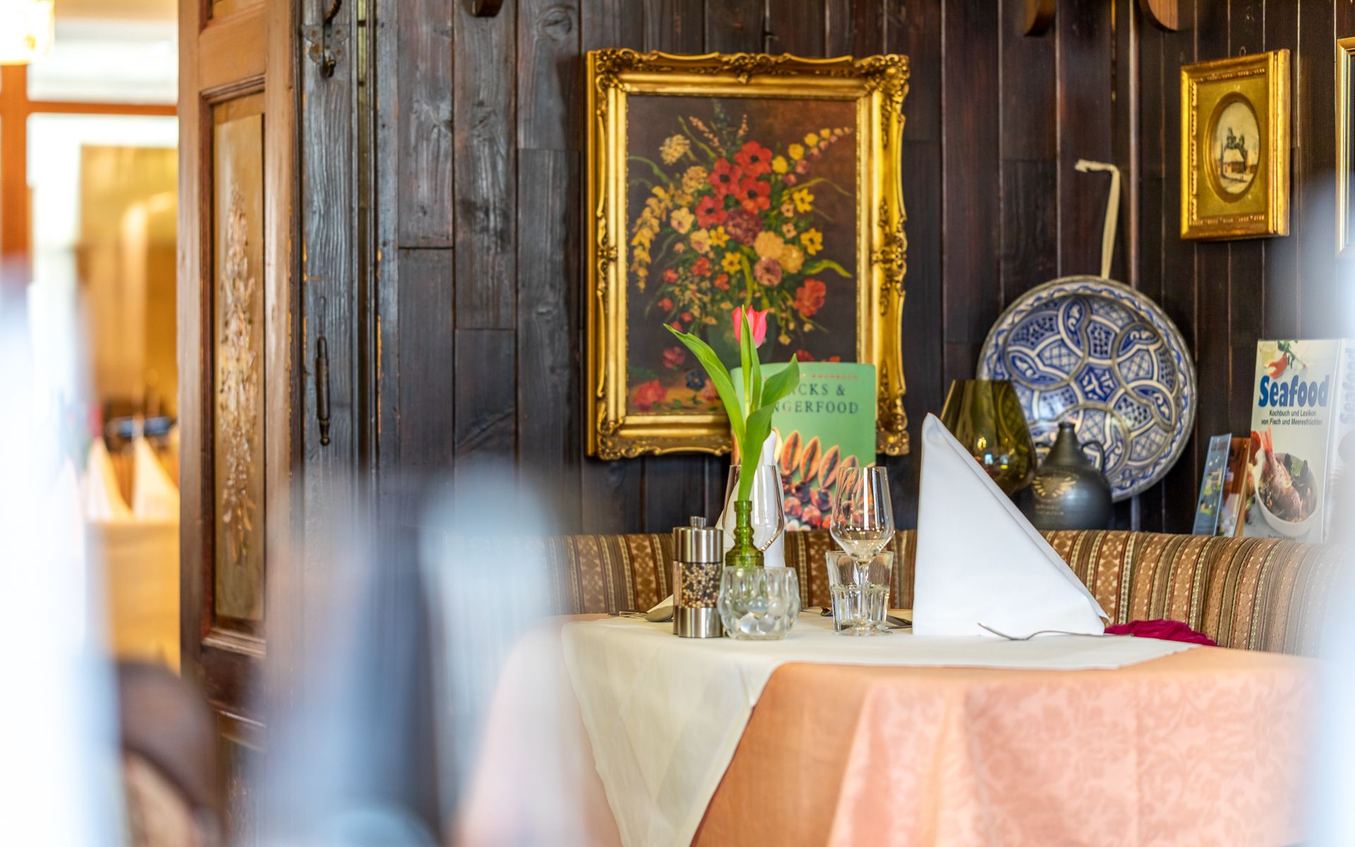 Gemütlich gedeckter Tisch in einem rustikalen Restaurant mit Blumenbild und Dekorationen an der Wand.
