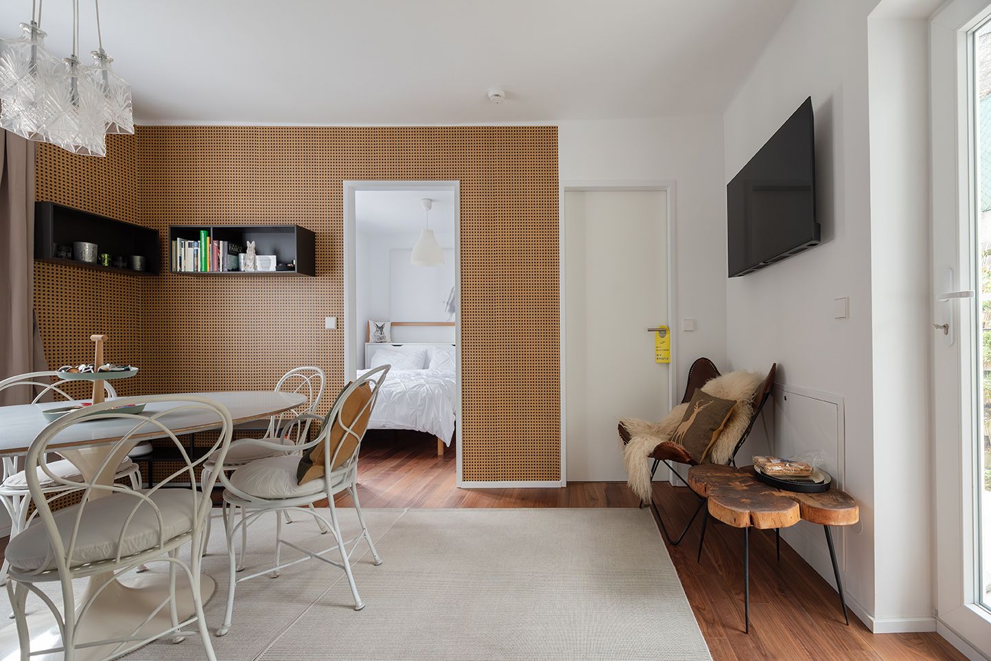 Innenansicht eines modern eingerichteten Wohnzimmers mit Esstisch, Stühlen und Zugang zu einem Schlafzimmer.