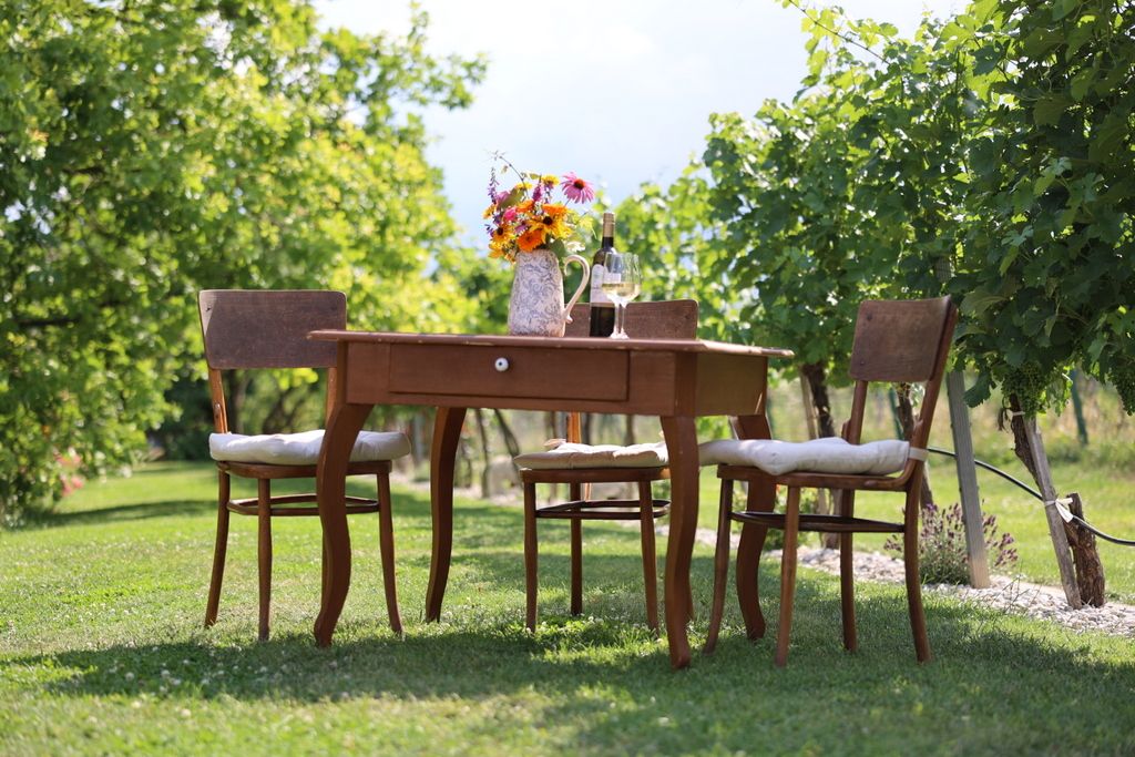 Ein Tisch mit Blumen und Wein in einem Weingarten.