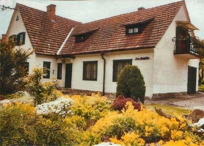 Ein weißes Haus mit rotem Ziegeldach und Garten voller gelber Blumen.